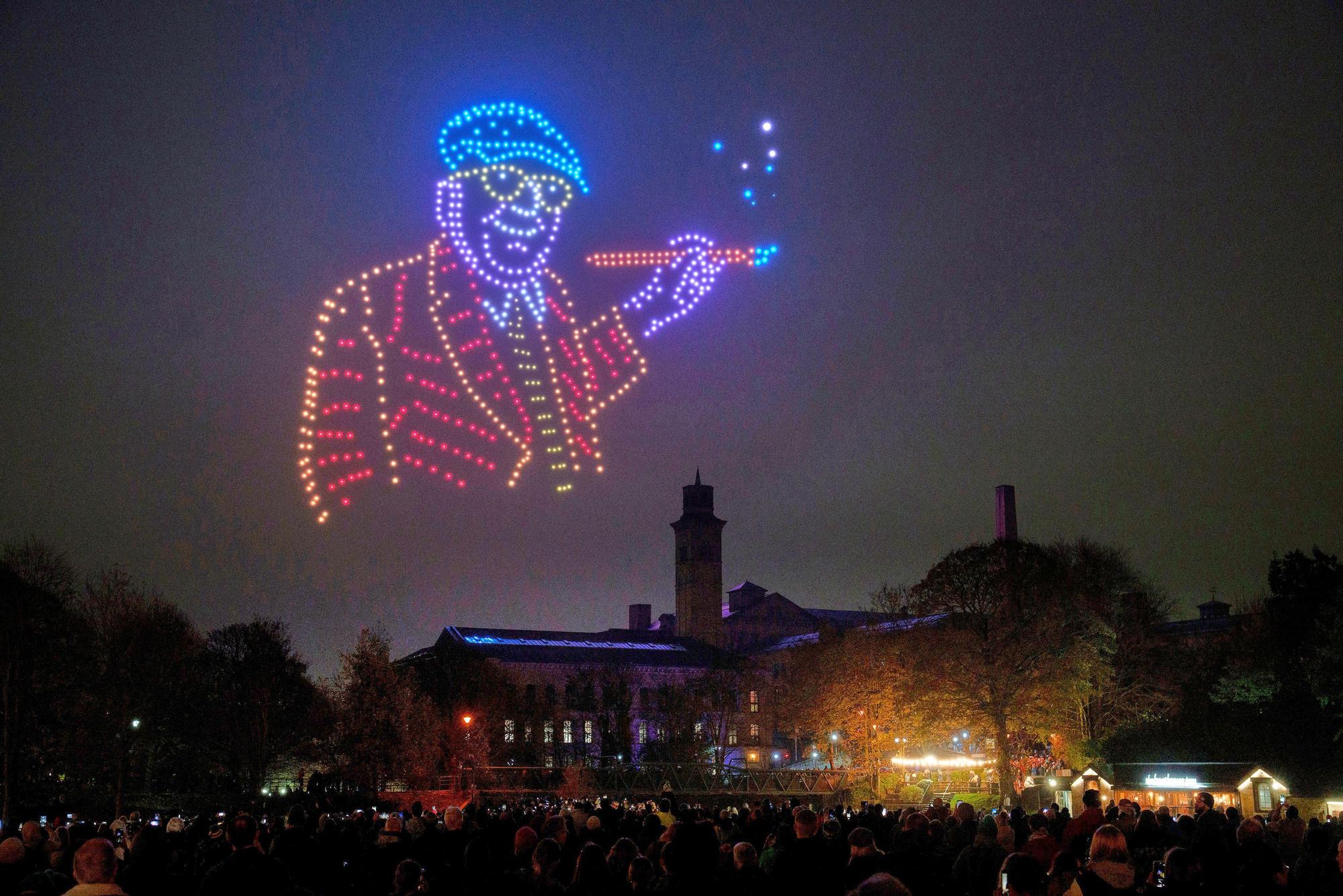 13.11.2025, Großbritannien, Bradford: Ein Selbstporträt von David Hockney bildet den Abschluss einer Drohnenshow, die eine digitale Auswahl von David Hockneys ikonischen Kunstwerken in seiner Heimatstadt Bradford, im Rahmen einer Sonderveranstaltung für «Bradford 2025 - UK City of Culture» zeigt.