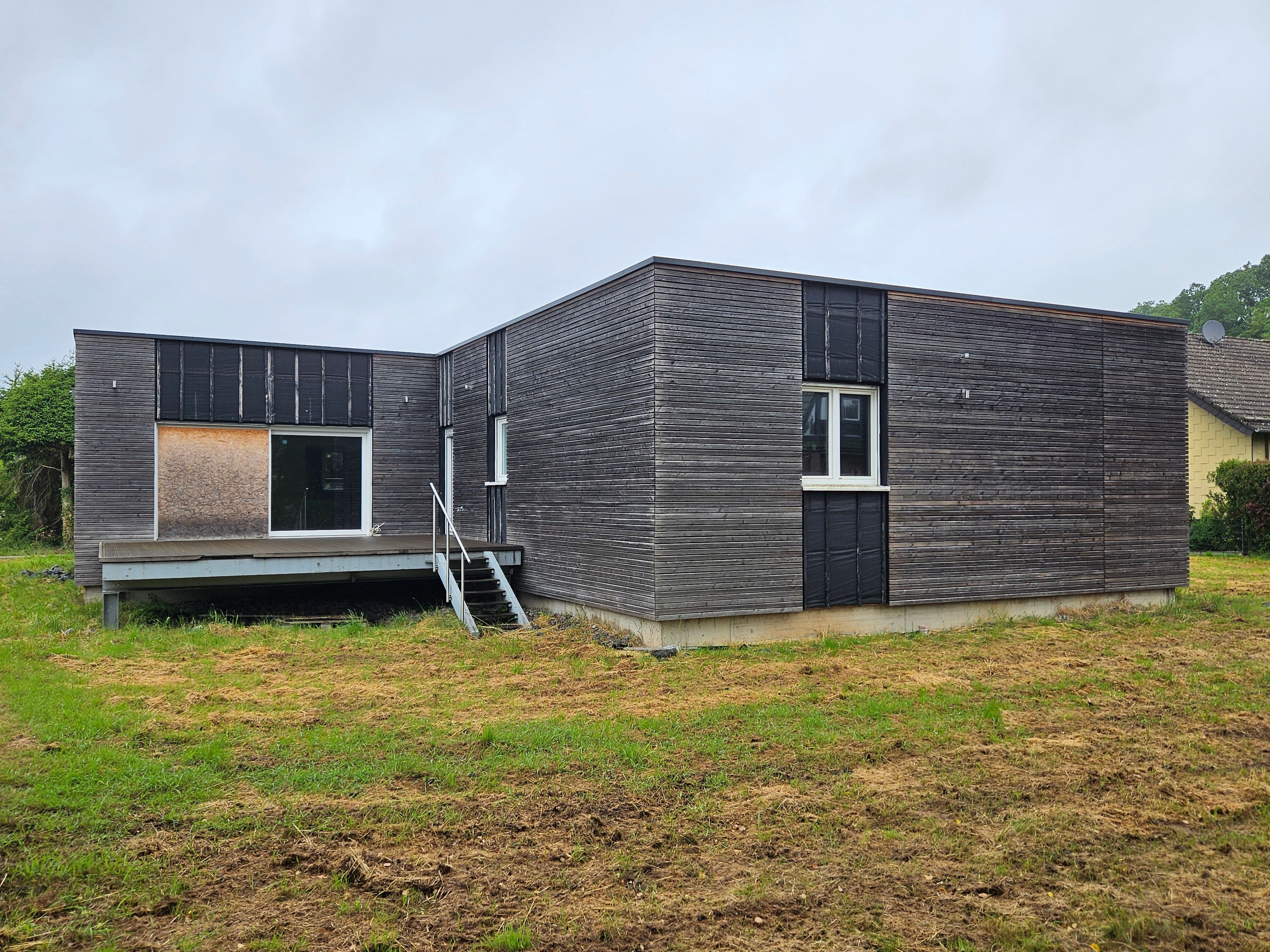 Blick auf das ehemalige Wohngebäude mit Holzfassade.