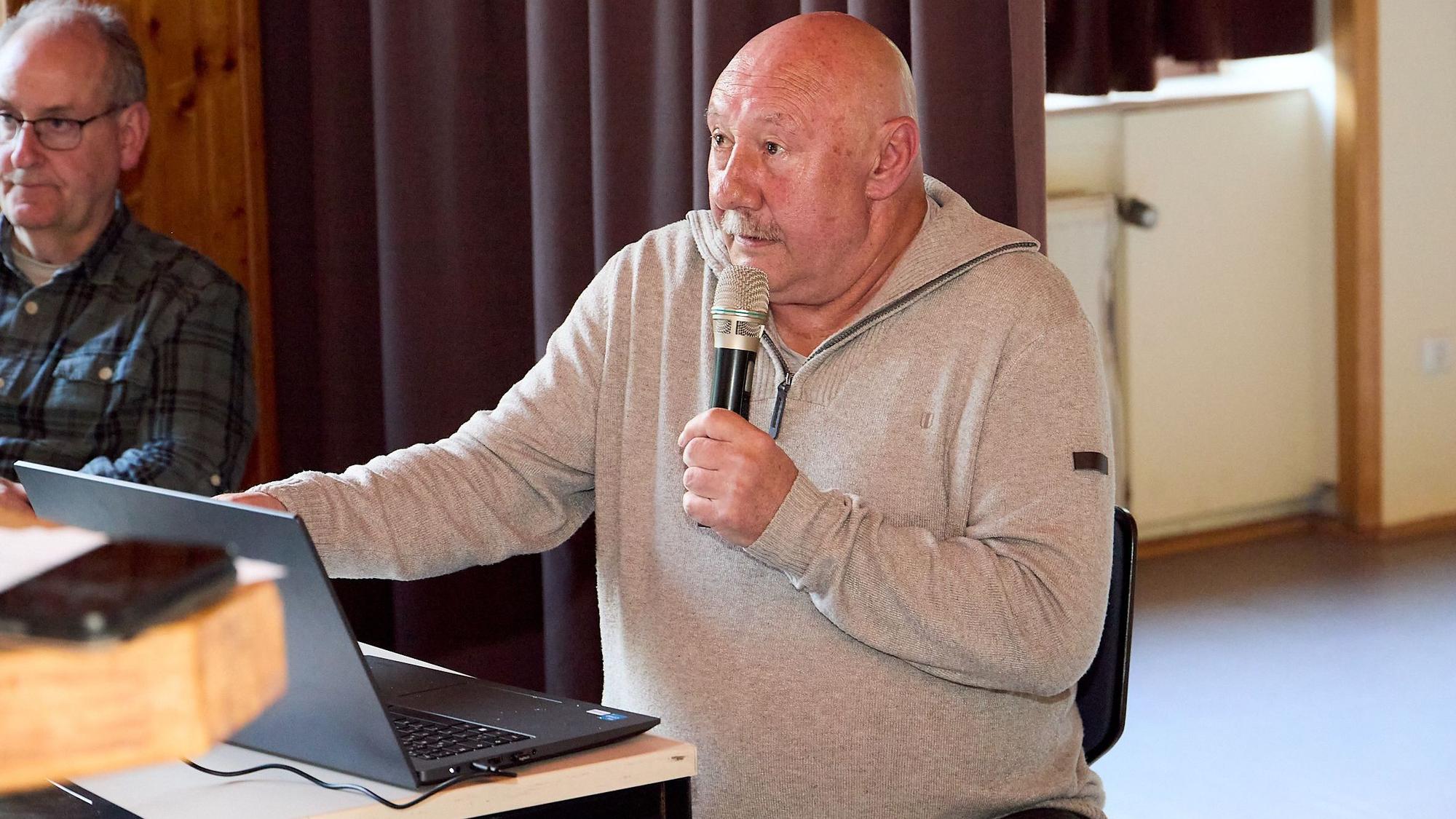 Journalist F.A. Heinen sitzt in einem hellen Pullover vor einem Laptop und spricht in ein Mikrofon.