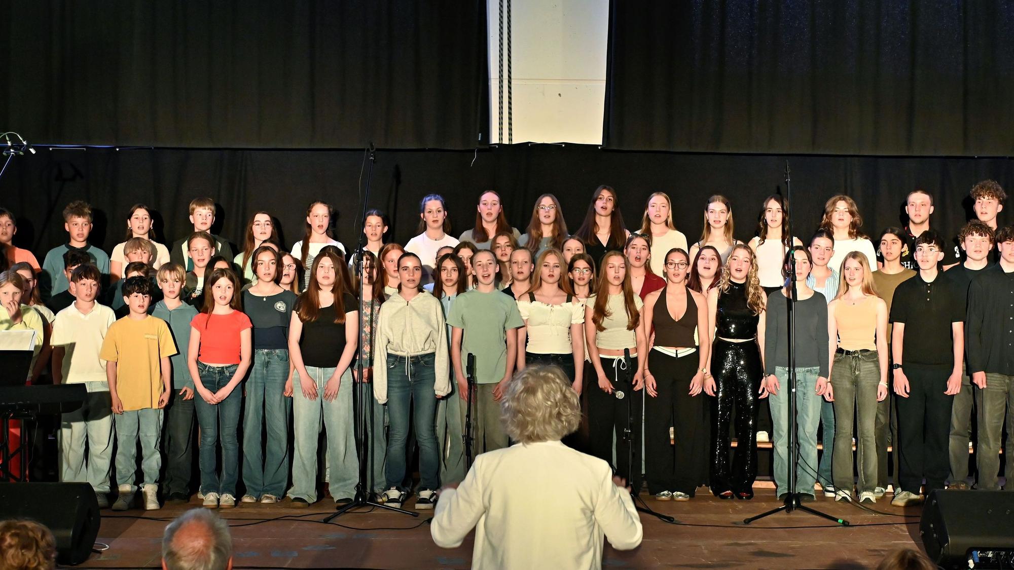 Ein Chor steht auf einer Bühne und singt.