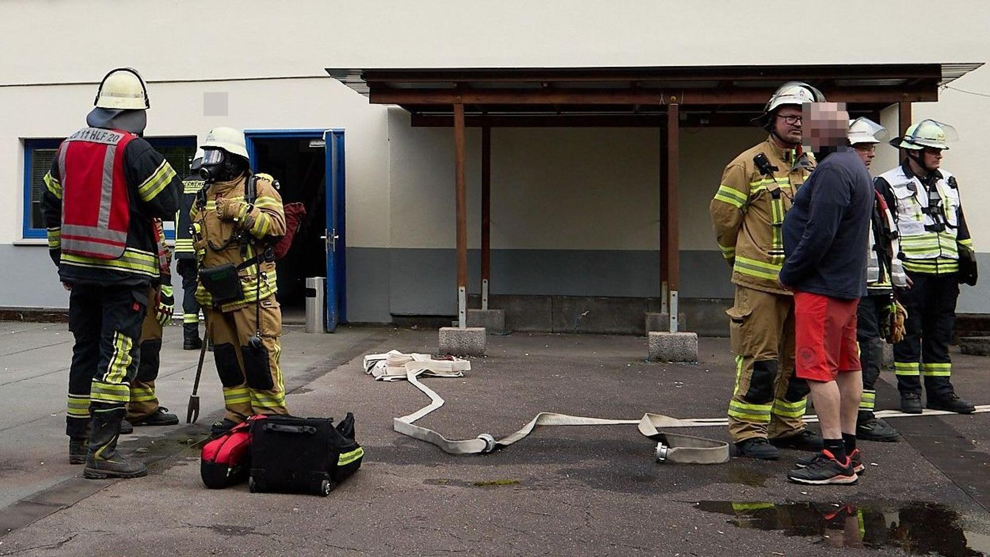 Feuerwehrleute stehen vor einem Gebäude.