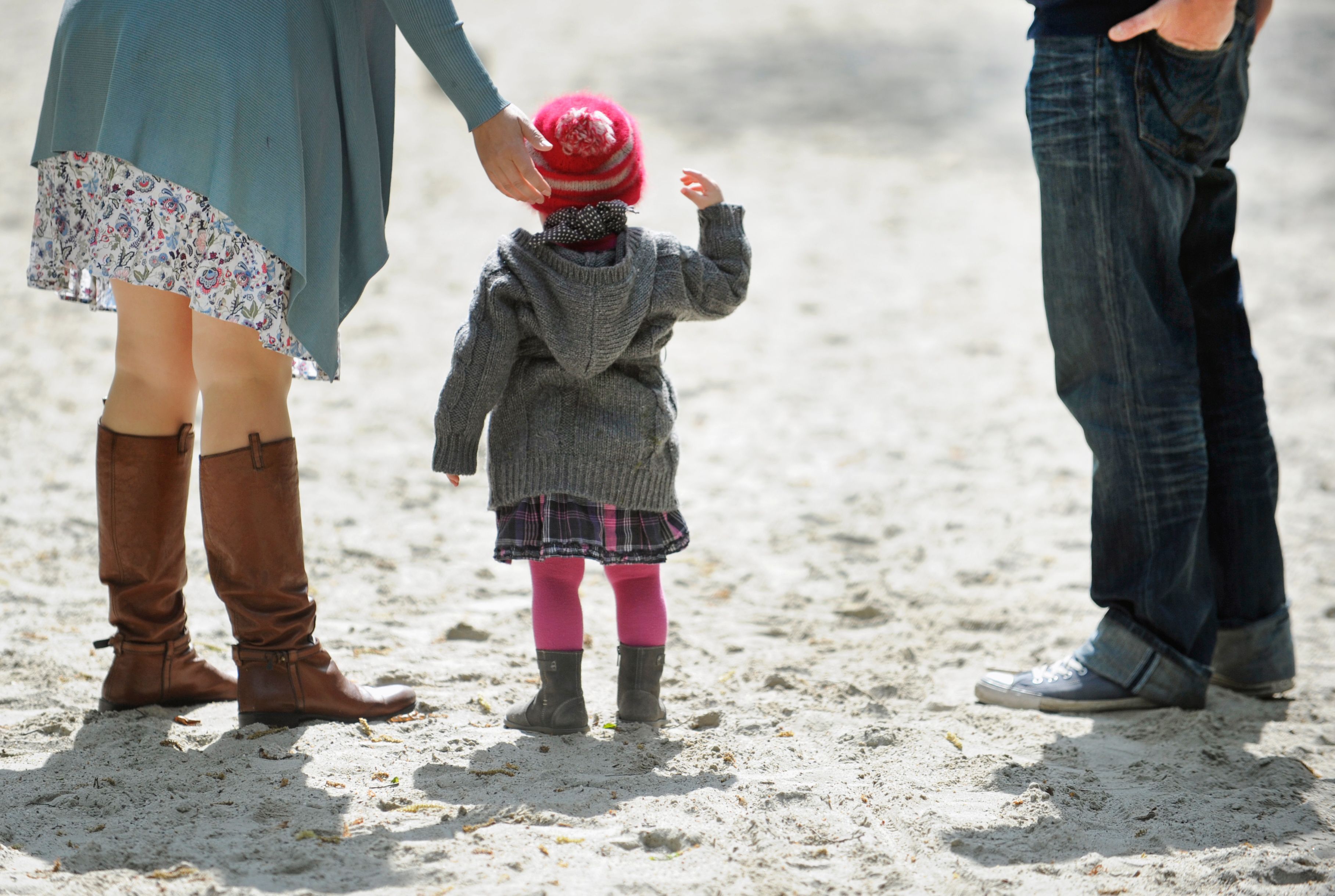 Ein Kind und seine Eltern stehen im Sand. Würden mehr Mütter Vollzeit arbeiten, käme das dem Rentensystem zugute, sagt der DIW-Präsident. (Symbolbild)