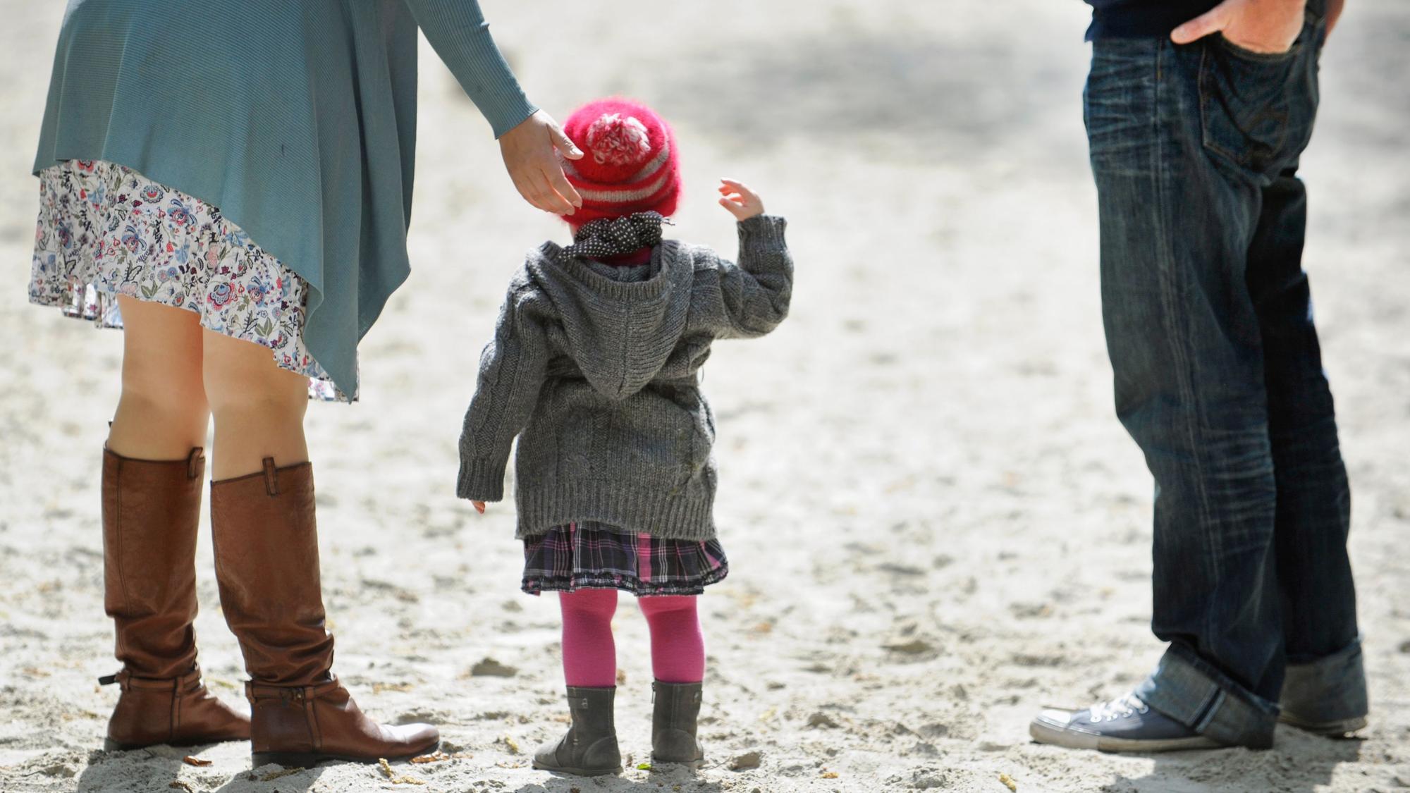 Ein Kind und seine Eltern stehen im Sand. Würden mehr Mütter Vollzeit arbeiten, käme das dem Rentensystem zugute, sagt der DIW-Präsident. (Symbolbild)