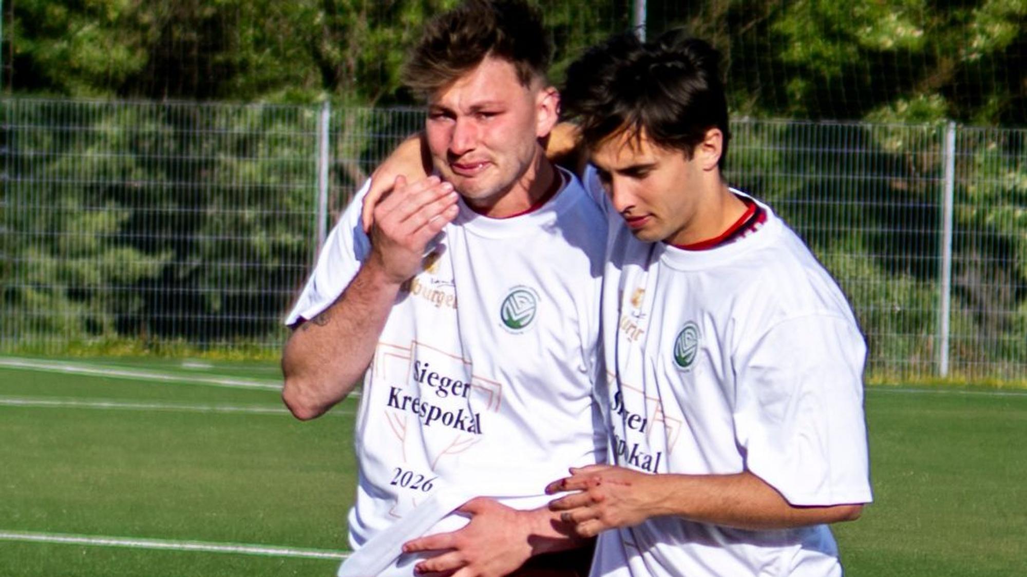 Das Bild zeigt den Obengenannten, der weint. Er wird von einem Mitspieler getröstet.