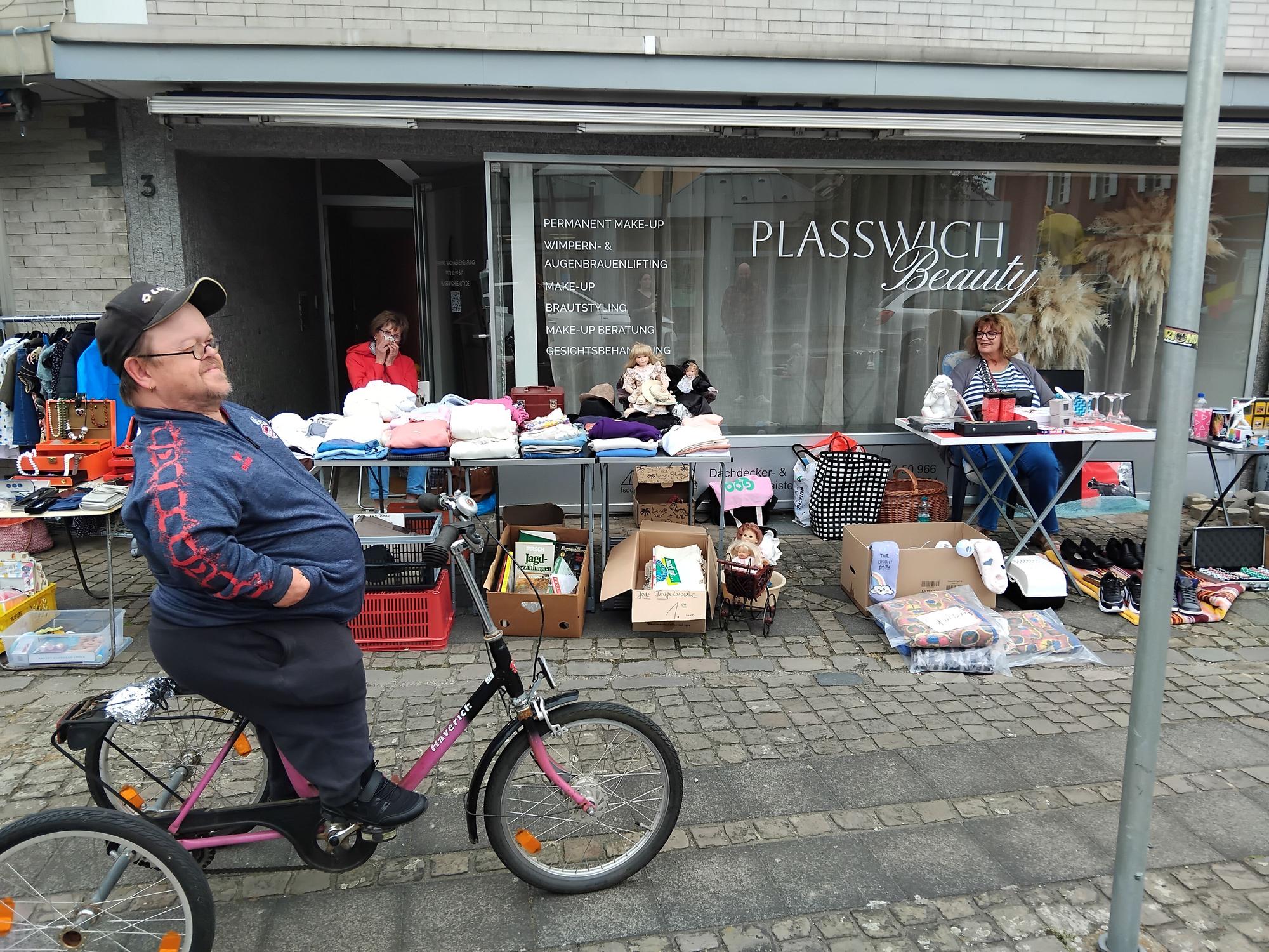 Ein Mann auf einem Fahrrad vor einem Flohmarktstand