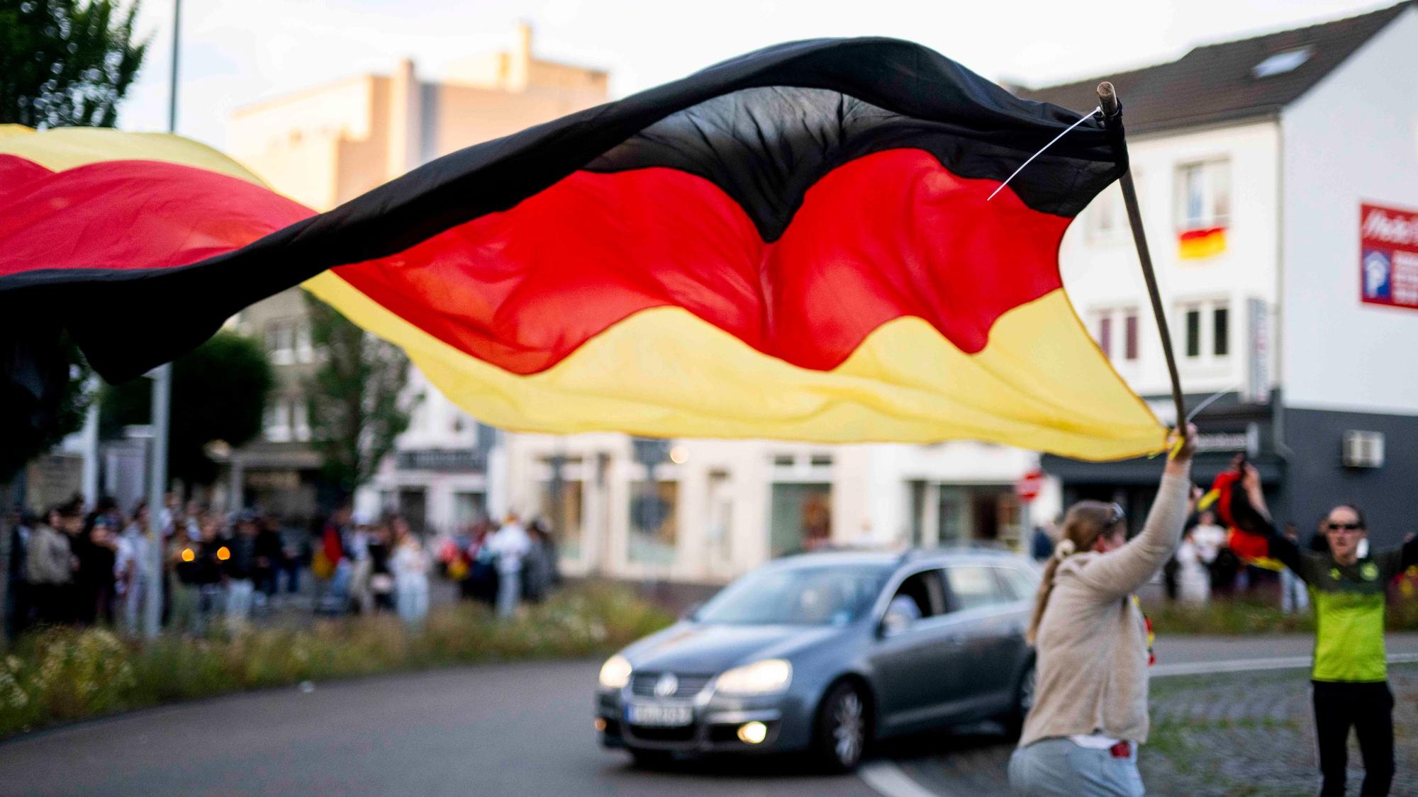 Eine Frau läuft mit einer riesiegen Deutschland-Fahne durch den Kreisel.