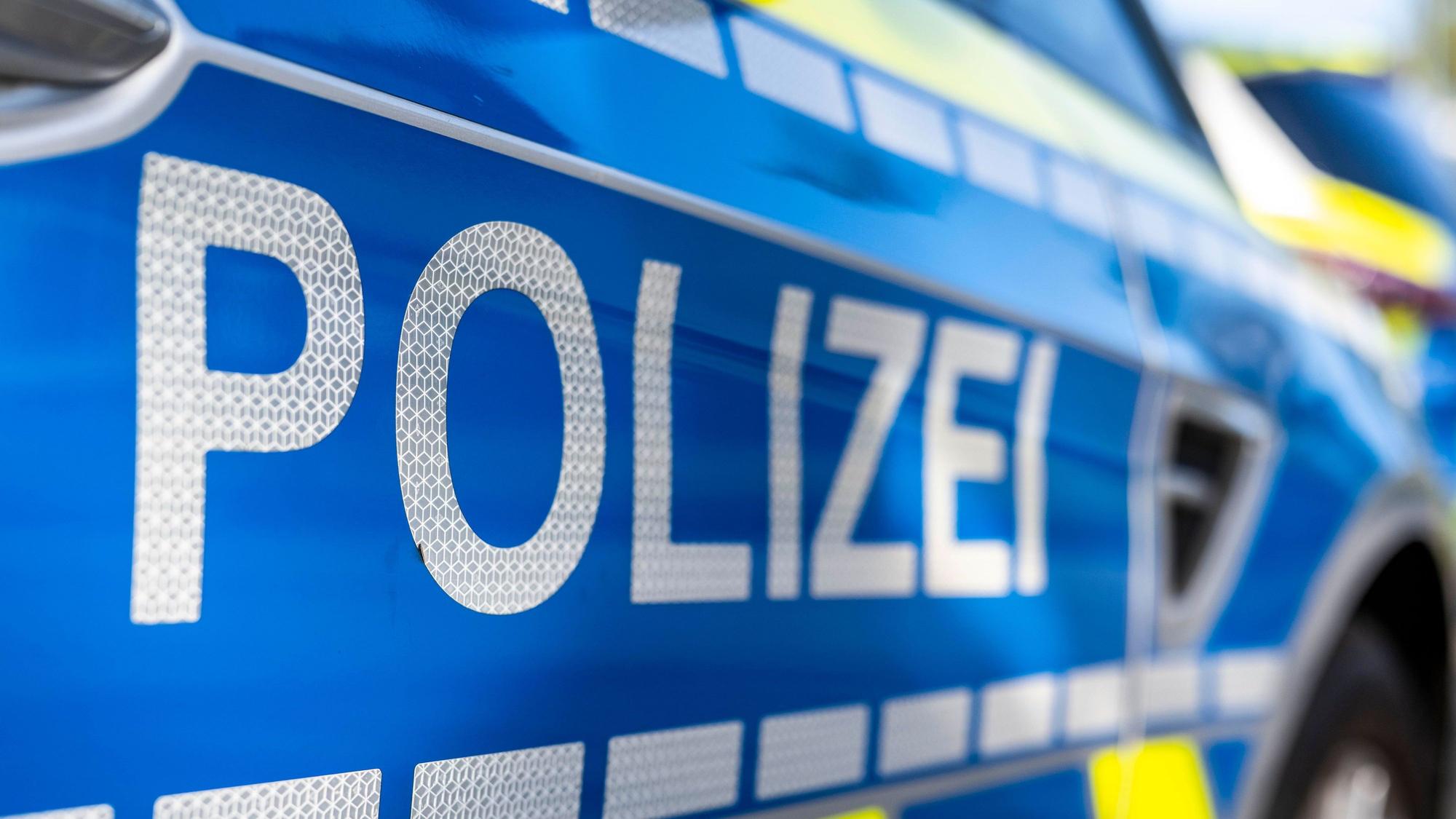 An der Tür von einem Streifenwagen steht der Schriftzug „Polizei“.