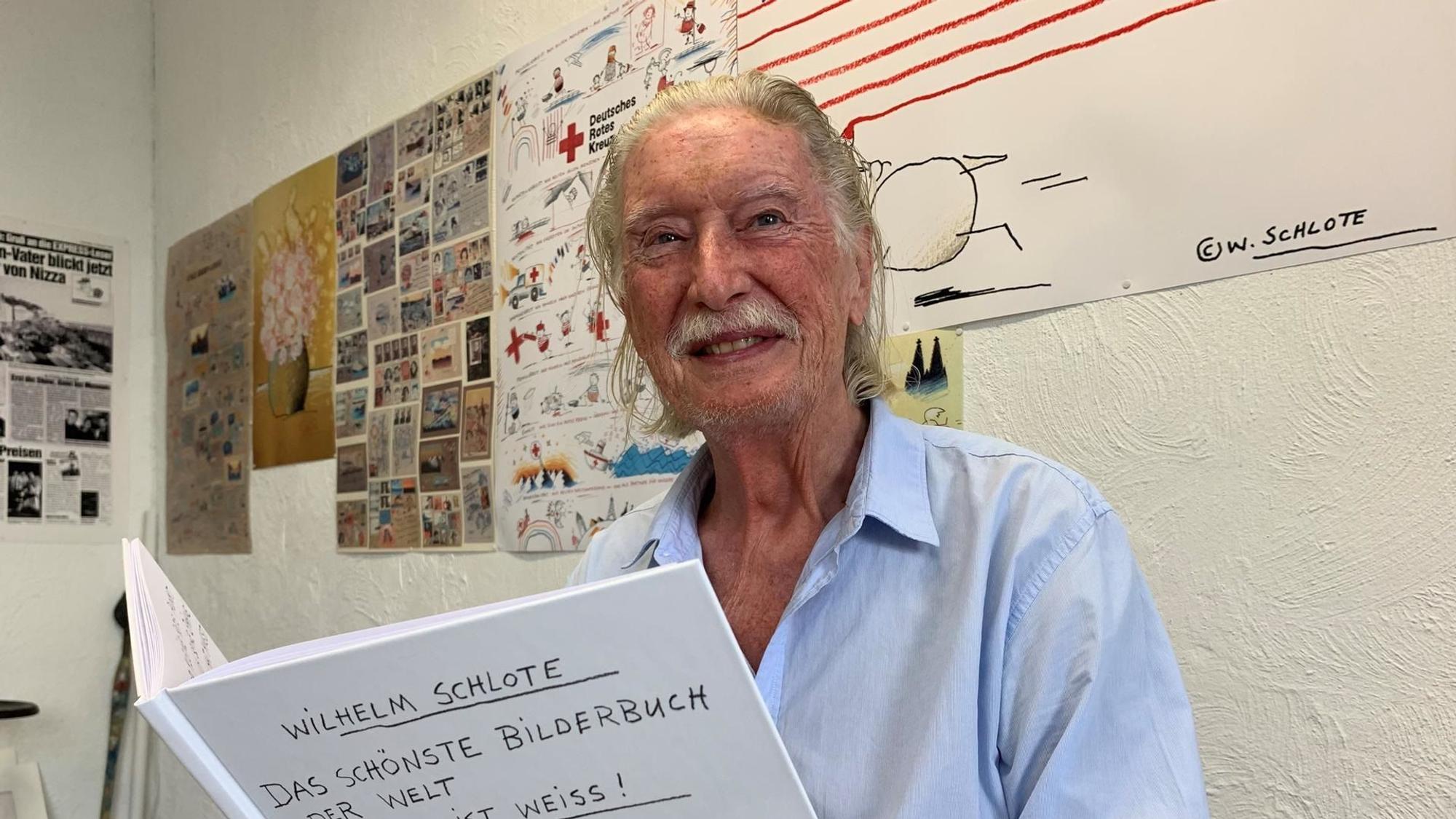 Ein alter Mann mit weißem Haar und Schurrbart hält ein weißes Buch.
