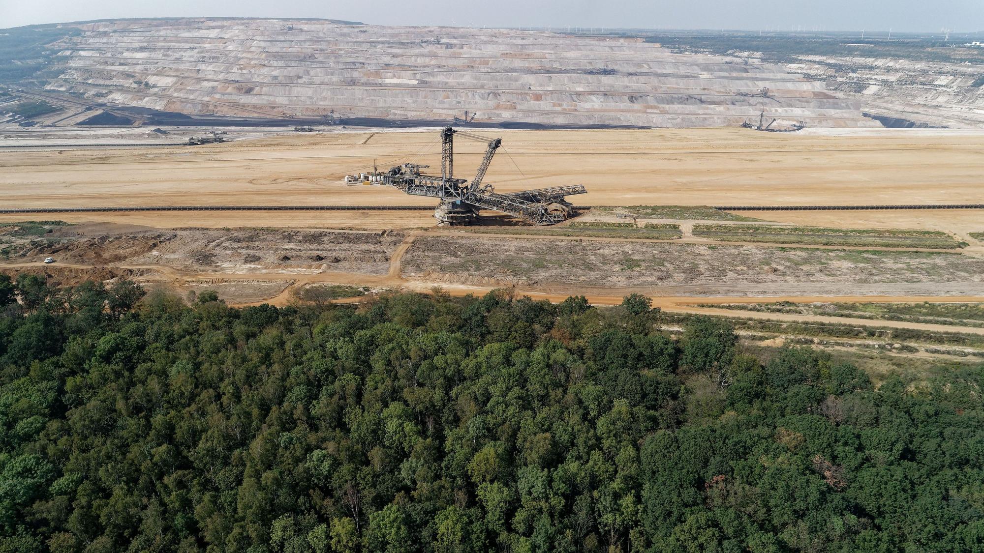 Das Foto zeigt den Tagebau Hambach mit einem Bagger, davor der Hambacher Forst.