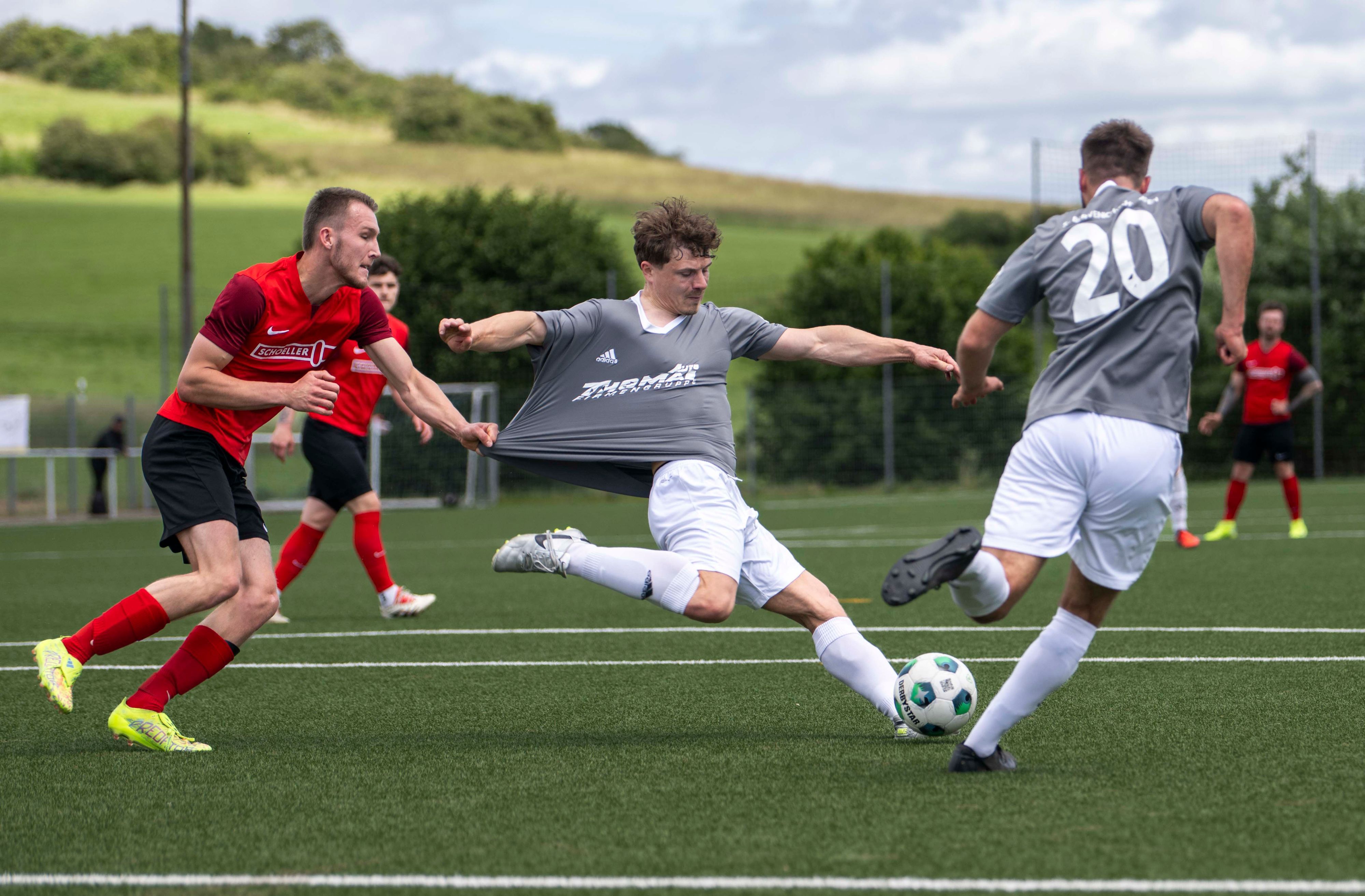 Ein Fußballer hält den ballführenden Gegenspieler am Trikot fest, das dadurch langgezogen wird.