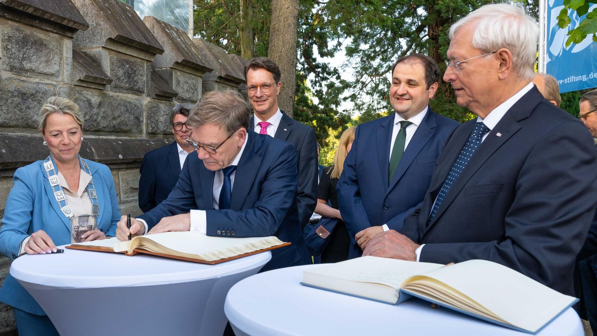 Außenminister Johann Wadephul (CDU) trägt sich beim Sommertreff der NRW-Stiftung auf Schloss Drachenburg ins Gästebuch ein. Links neben ihm die Bürgermeisterin von Königswinter, Heike Jüngling (CDU). Weiter sind auf dem Bild: KStA-Chefredakteur Gerald Selch (verdeckt), NRW-Ministerpräsident Hendrik Wüst, der Chef der Staatskanzlei in Düsseldorf, Nathanael Liminski, und Eckhard Uhlenberg, Präsident der NRW-Stiftung (alle drei CDU, von links)