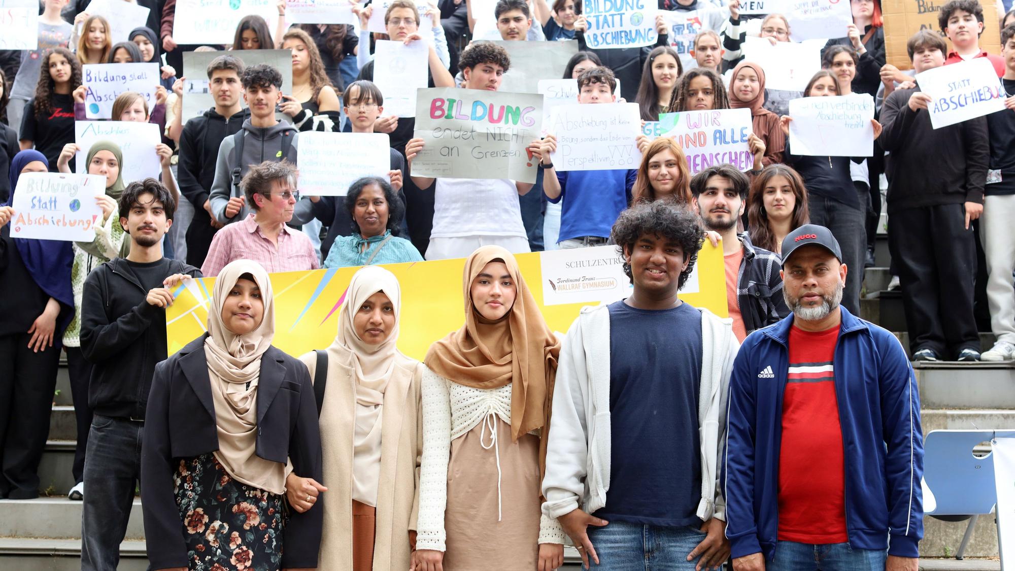 Familie Rouf aus Sri Lanka, dahinter Schüler mit Plakaten