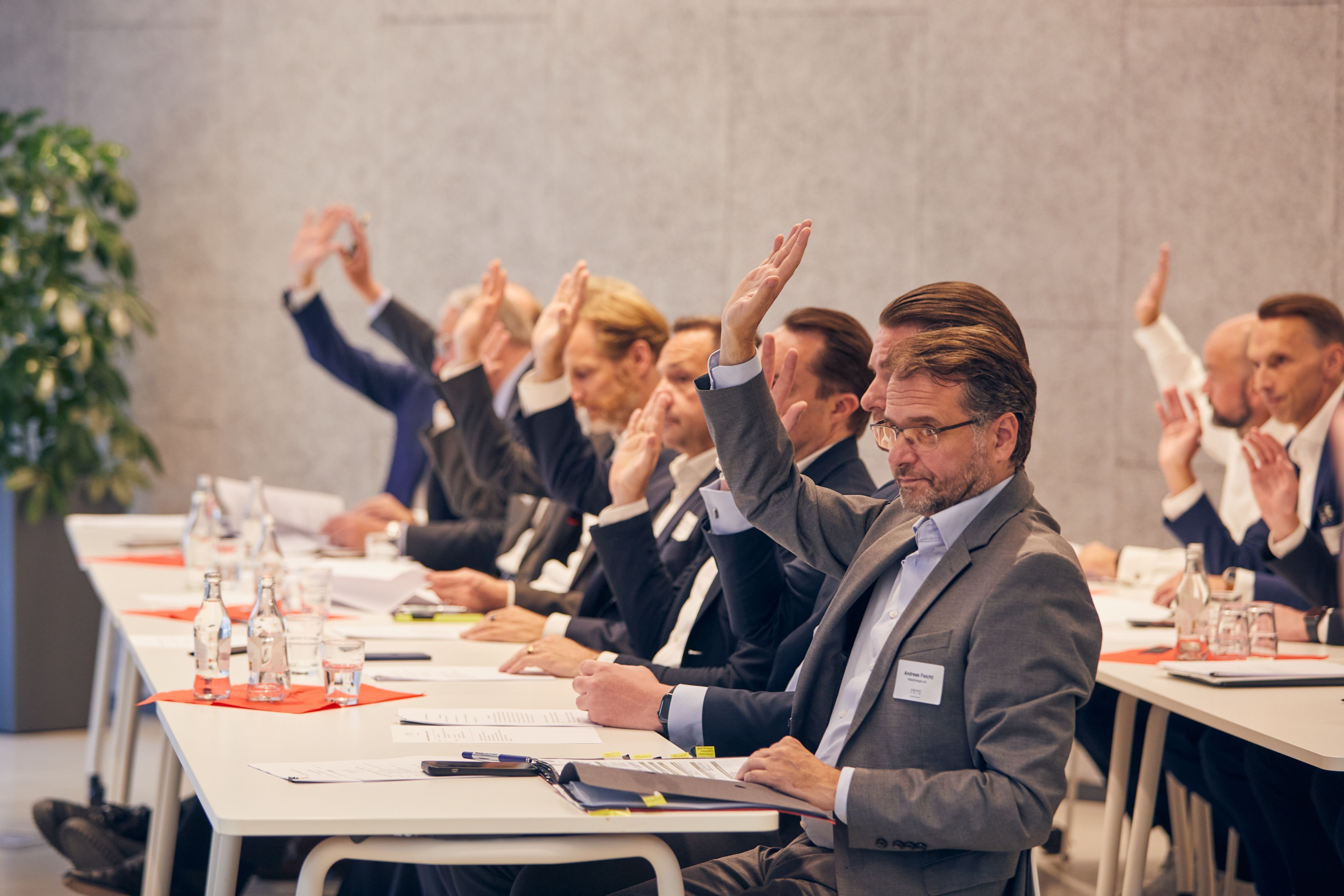 Die Vertreter der an der Initiative beteiligten Unternehmen signalisieren mit erhobenen Händen ihre Zustimmung zur Satzung