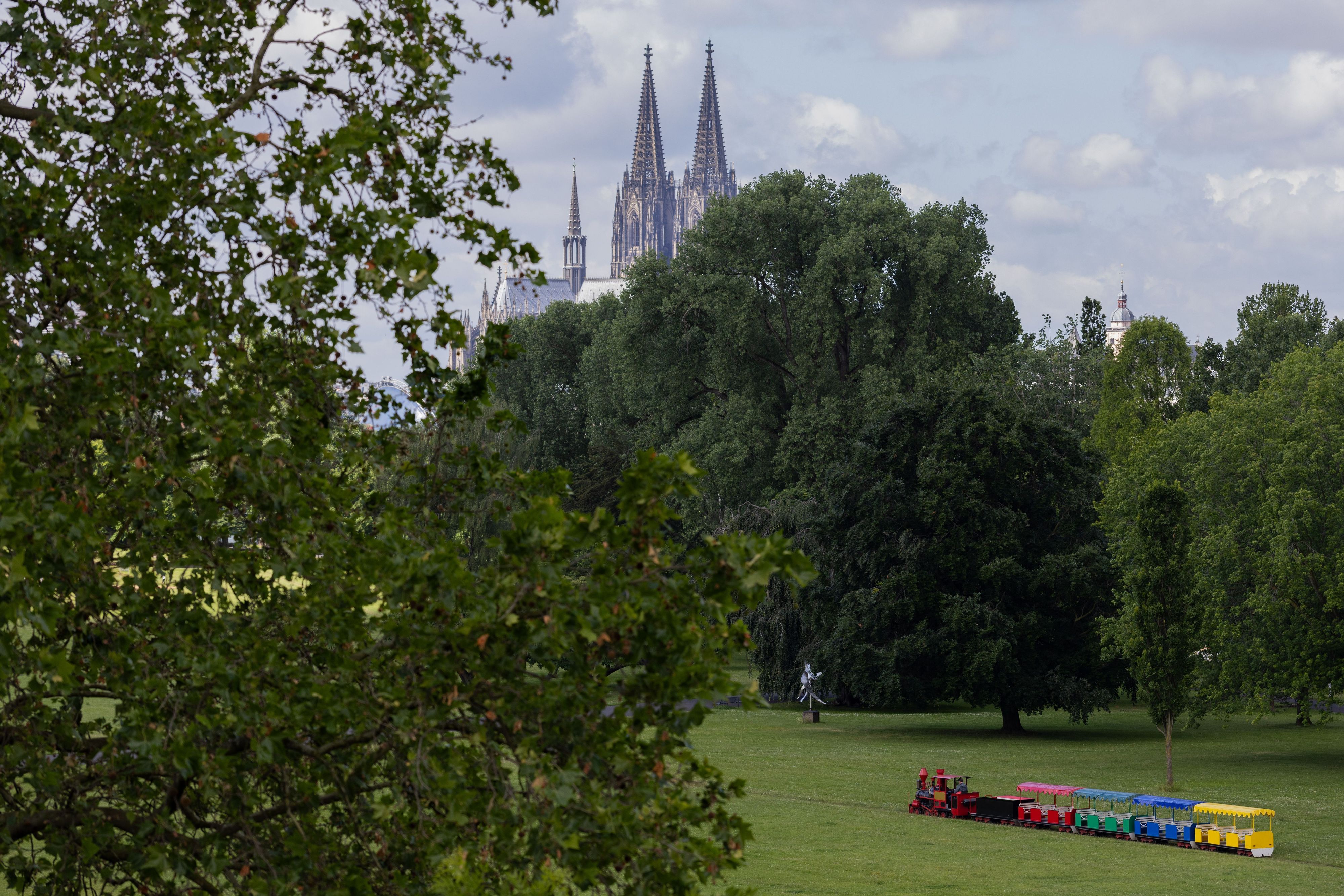 09.06.2026, Nordrhein-Westfalen, Köln: Die Kleinbahn im Rheinpark fährt bei wechselhaftem Wetter vor der Kulisse des Doms. Foto: Rolf Vennenbernd/dpa +++ dpa-Bildfunk +++