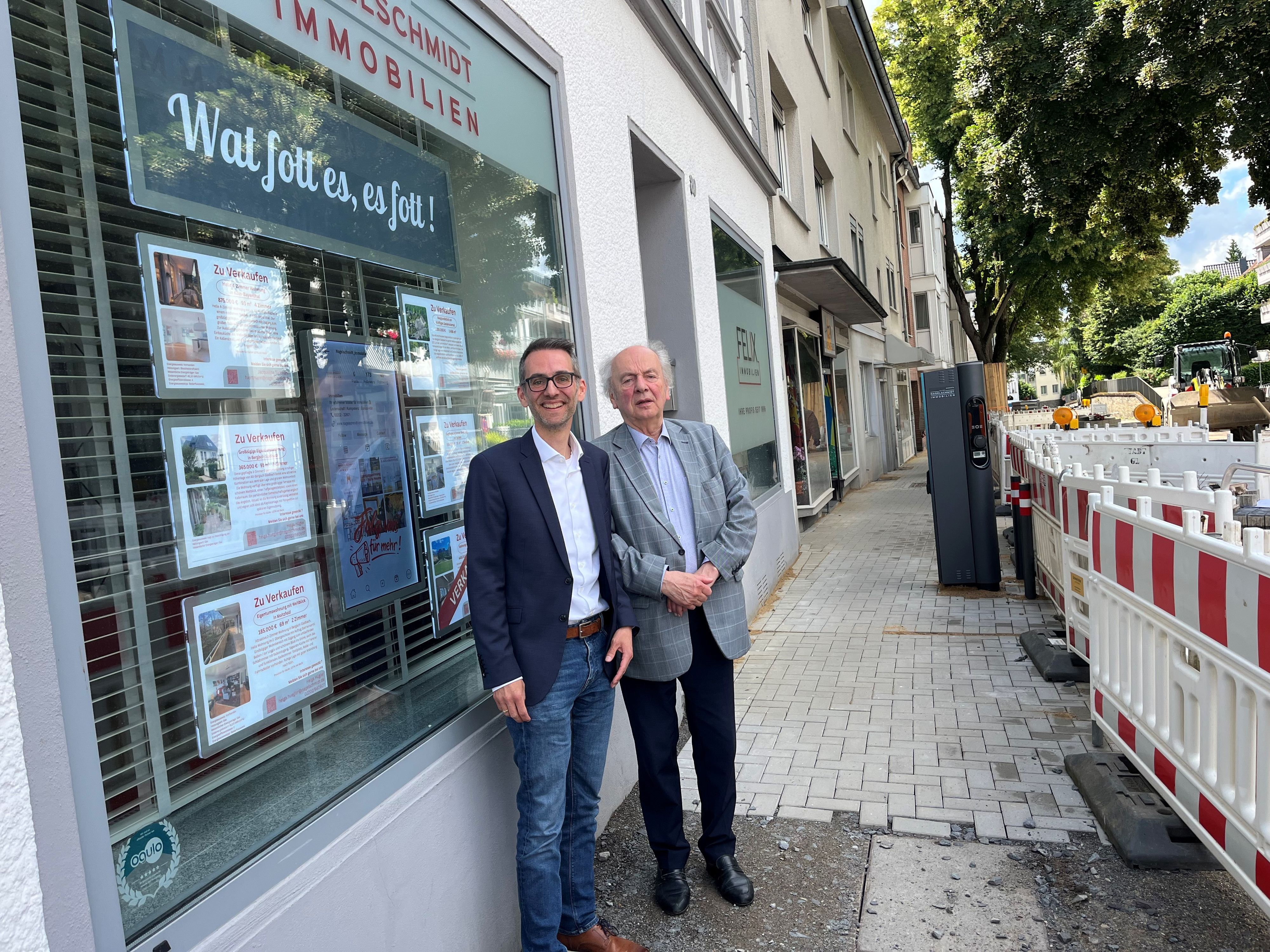 Die beiden Männer stehen vor einem Schaufenster.