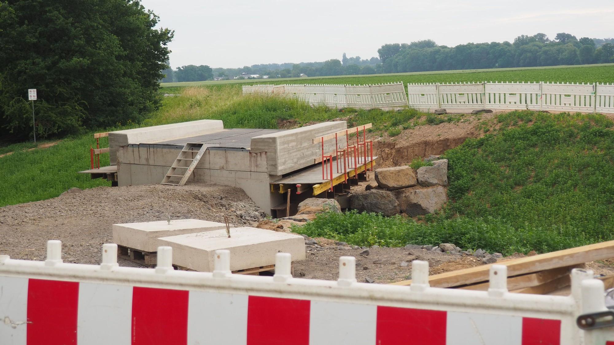 Hinter einer Absperrbake steht eine Brücke, die noch nicht an einen Weg angebunden ist.