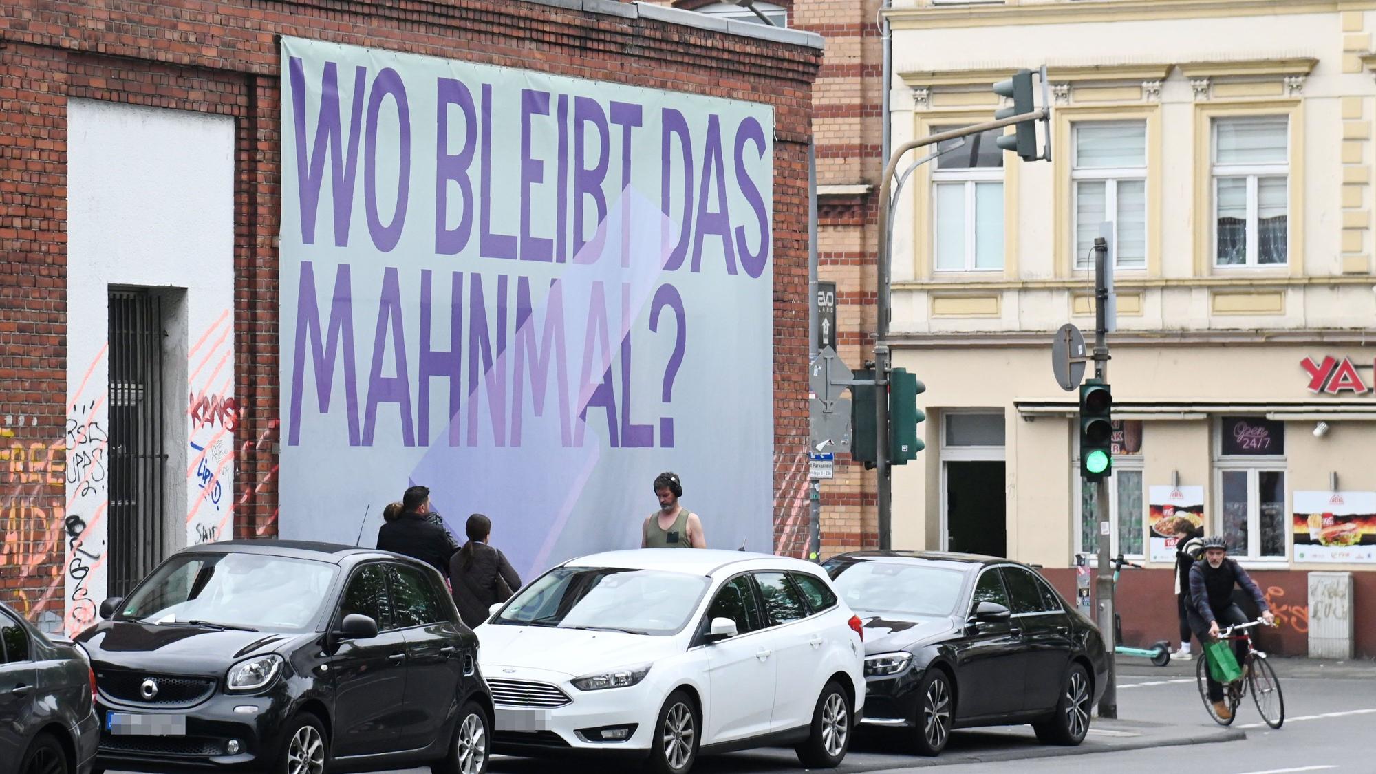An der Keupstraße hängt ein Transparent „Wo bleibt das Mahnmal?“. Es soll auf das bislang nicht realisierte Denkmal zum Anschlag des NSU in der Keupstraße im Jahr 2004 hinweisen.