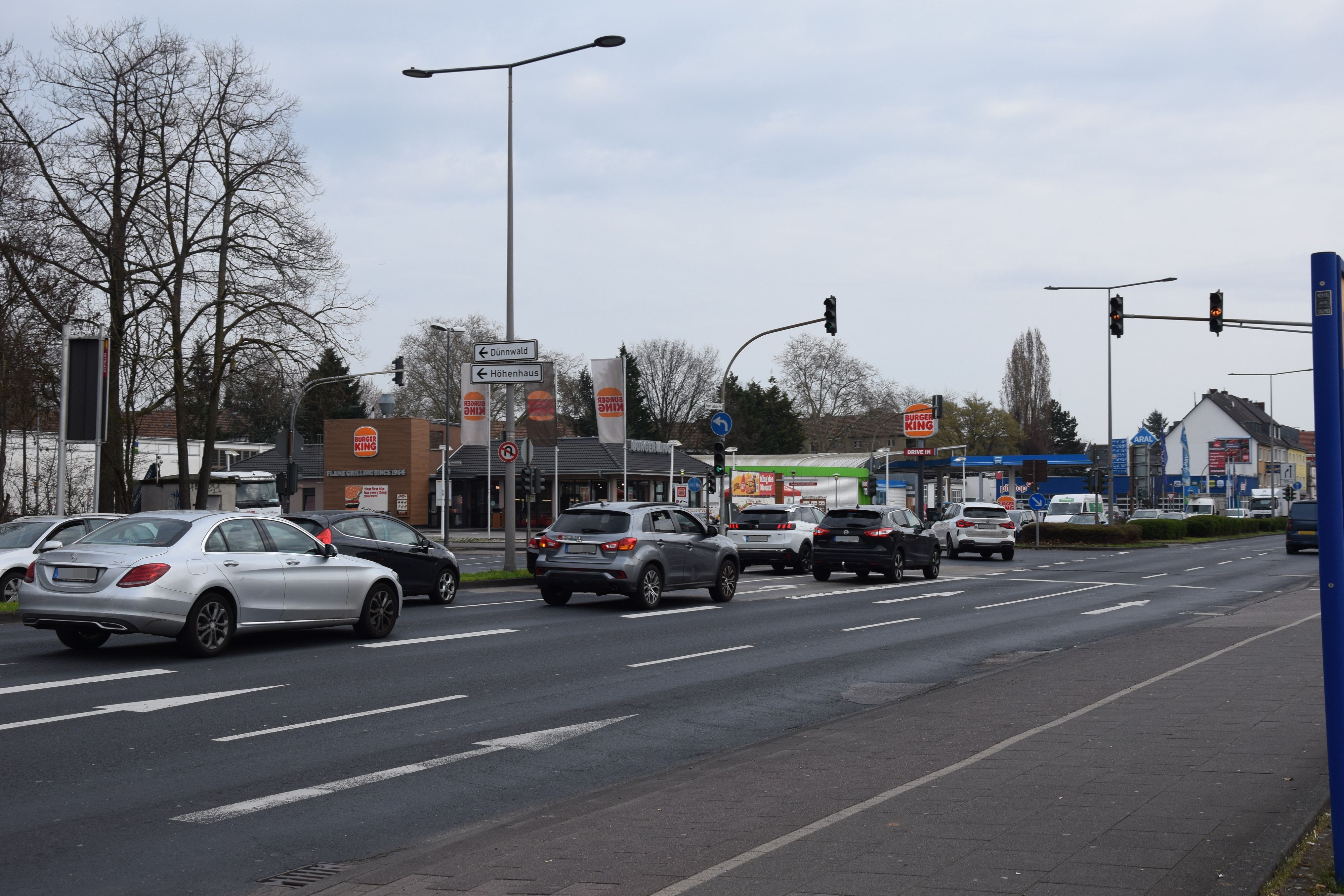 Auf einer mehrspurigen Straße stehen Autos an einer Ampelkreuzung.