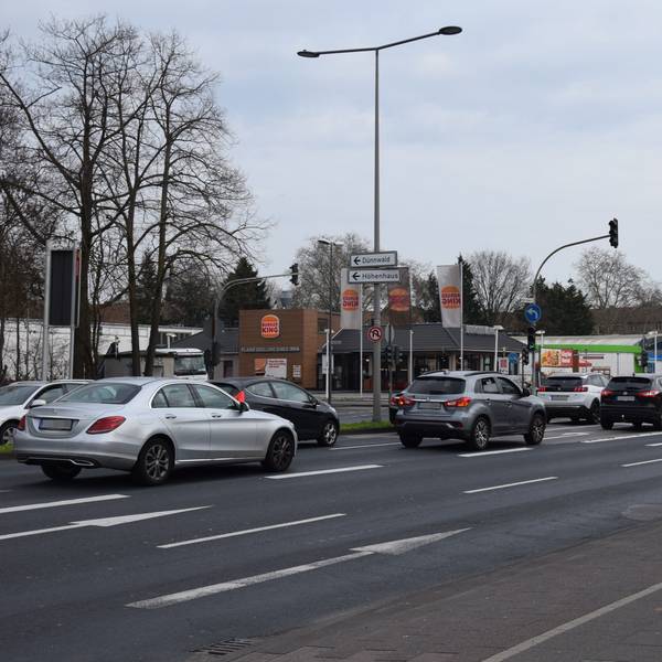 Auf einer mehrspurigen Straße stehen Autos an einer Ampelkreuzung.