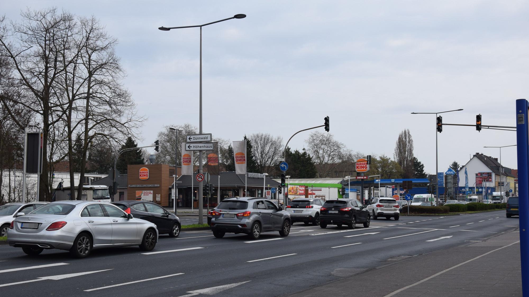 Auf einer mehrspurigen Straße stehen Autos an einer Ampelkreuzung.