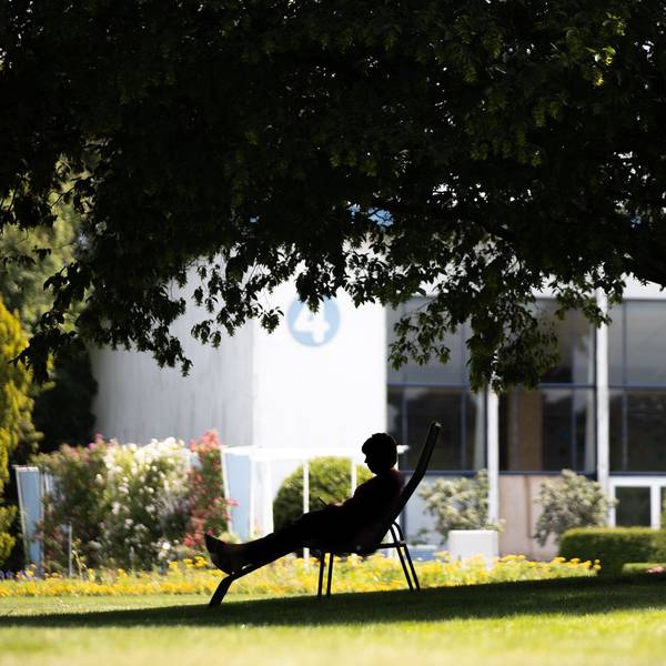 Frau sitzt bei Hitze im Schatten in einem Park