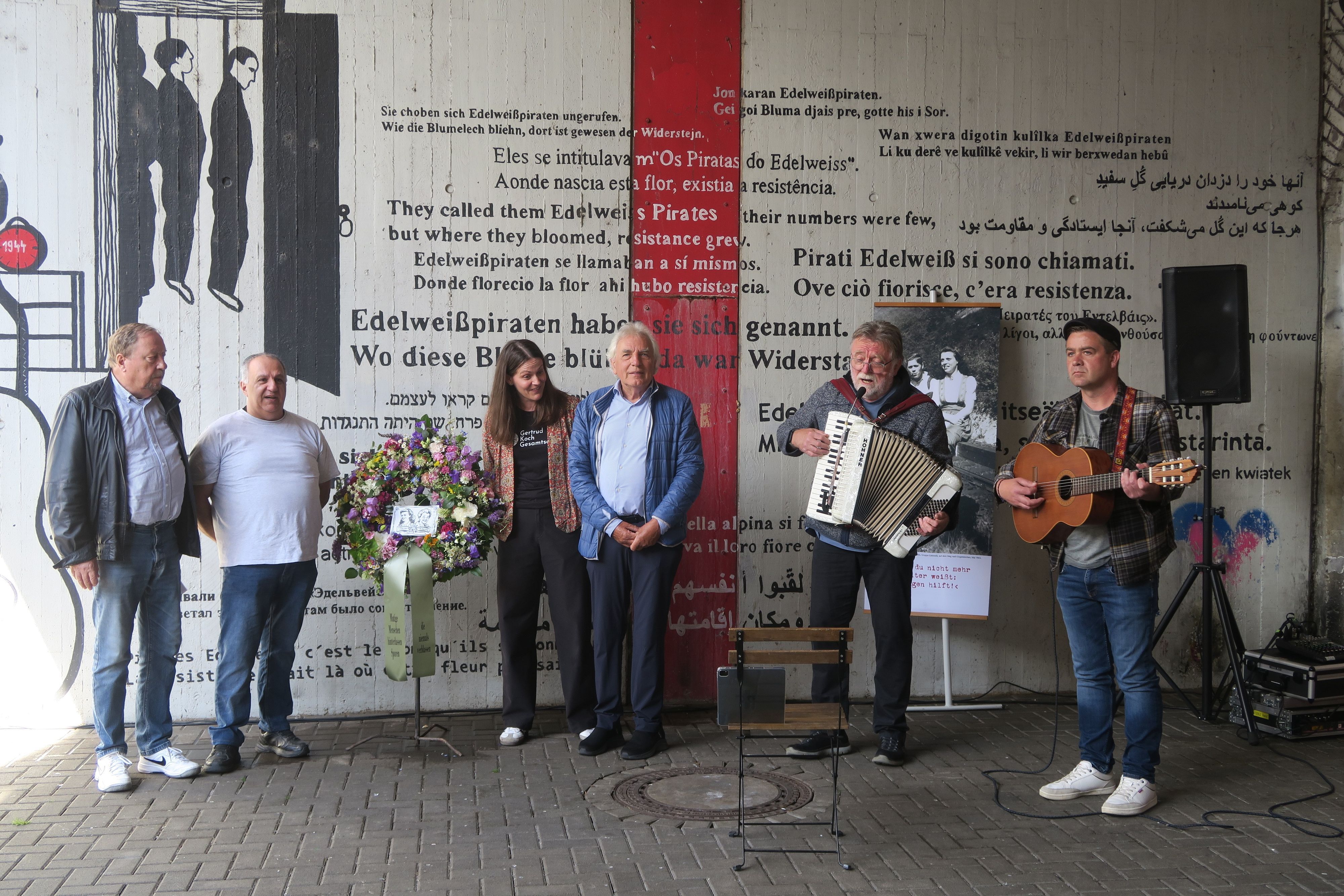 Fünf Männer und eine Frau stehen am Denkmal für die Edelweißpiraten in Köln-Ehrenfeld.