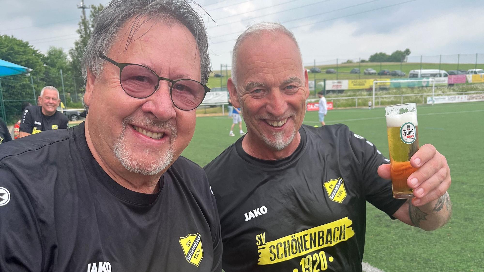 Ein Fußballtrainer und ein Vereinsvorsitzender stoßen miteinander an.