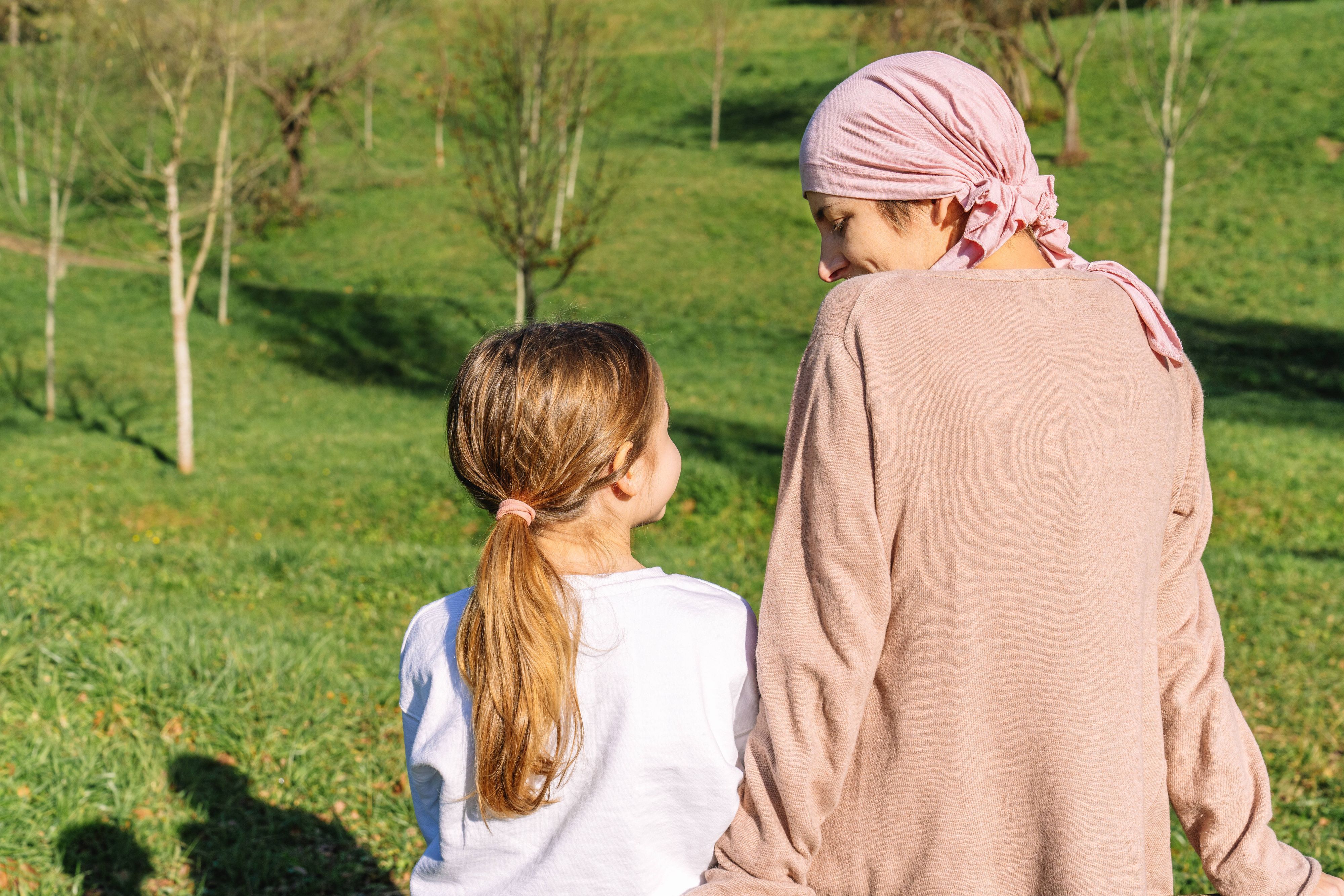 Mutter und Kind sitzen auf einer Wiese, man sieht sie nur von hinten.