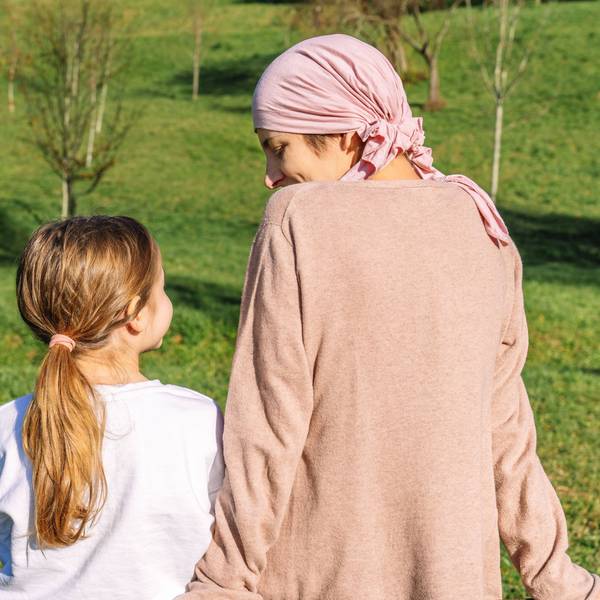 Mutter und Kind sitzen auf einer Wiese, man sieht sie nur von hinten.