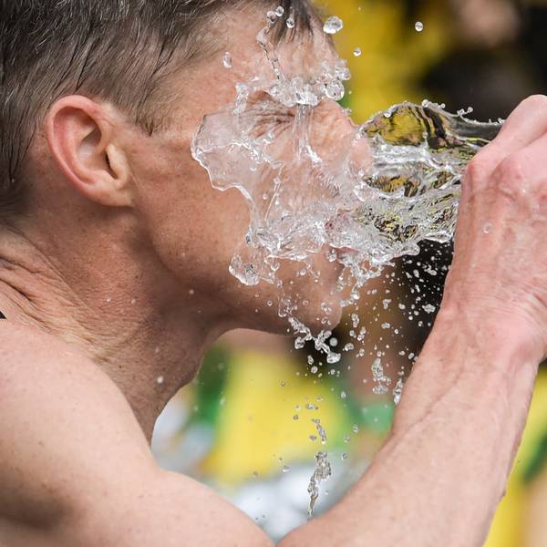 Ein Mann, vermutlich ein Sportler, schüttet sich einen Becher Wasser ins Gesicht.