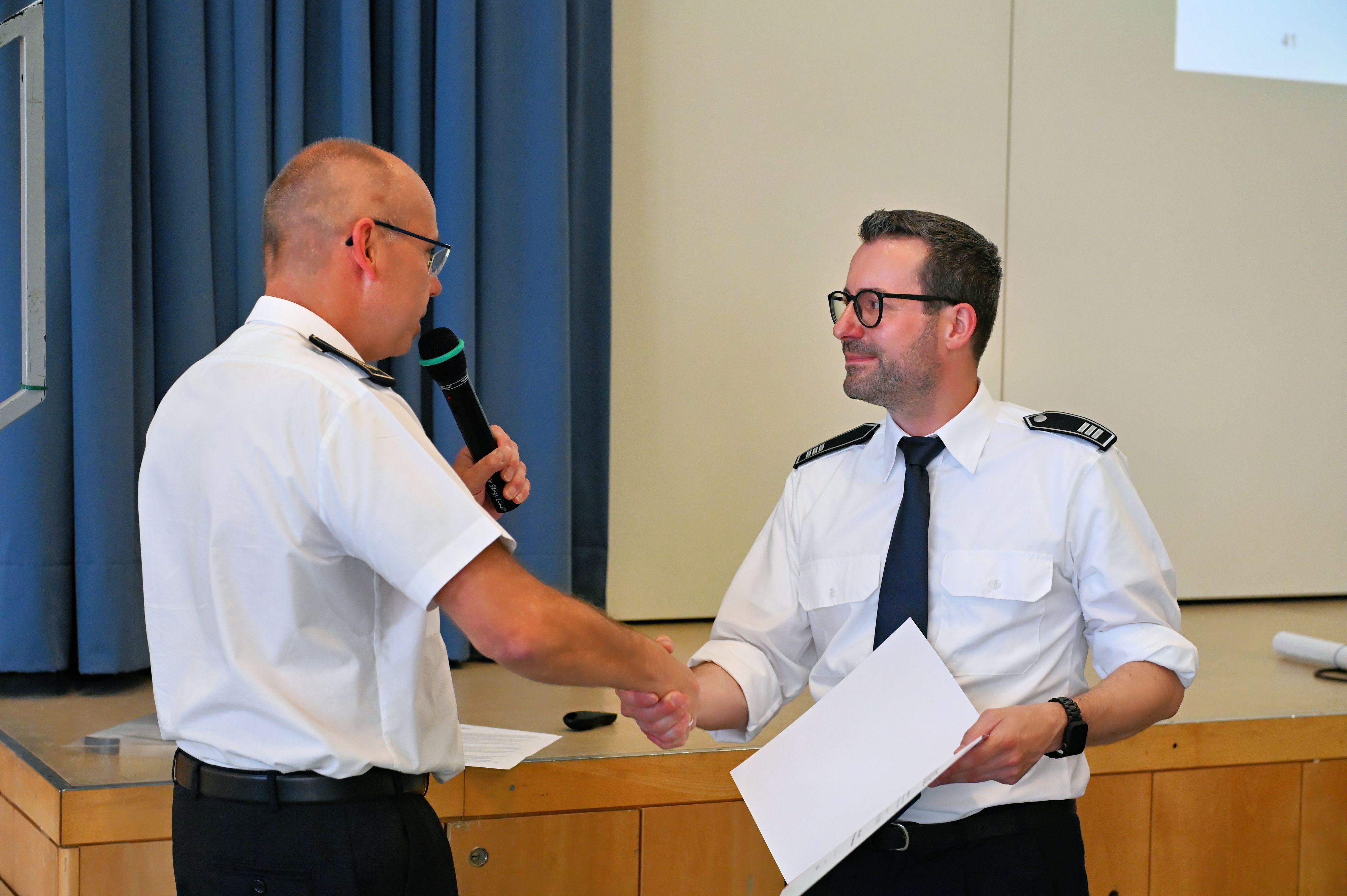 Zwei Feuerwehrleute in weißen Uniform-Hemden geben sich die Hand.