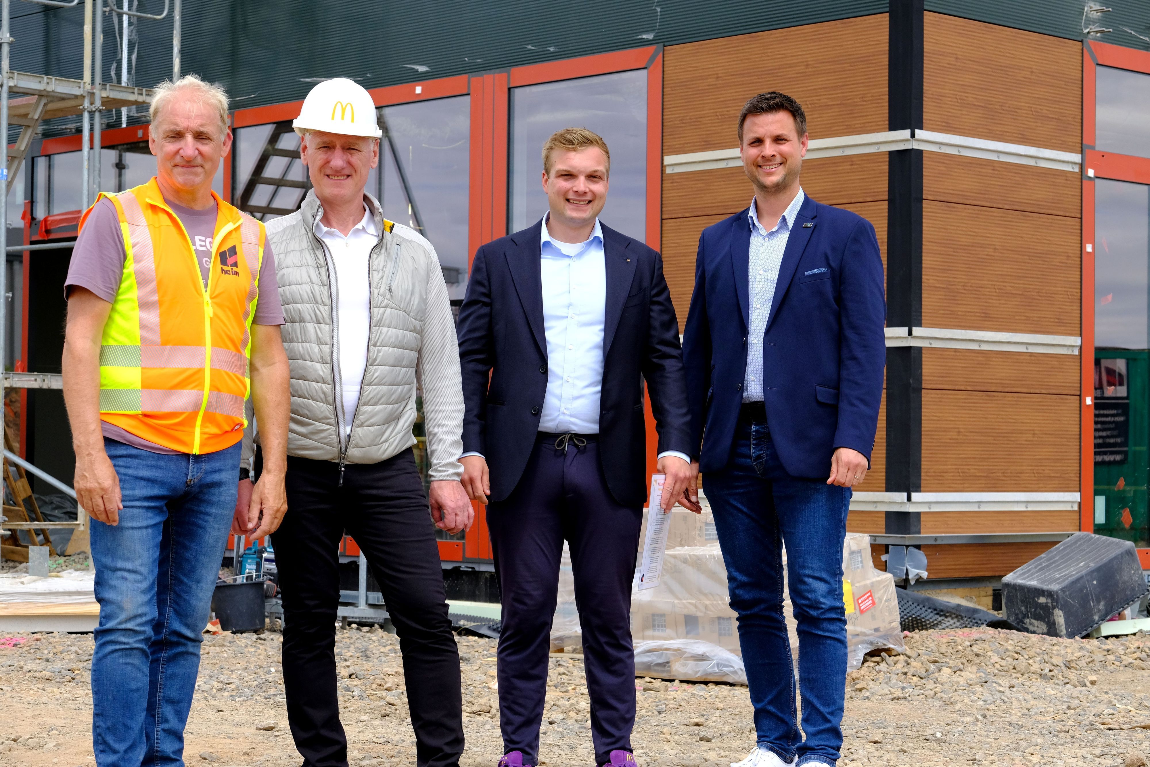 Die genannten Personen stehen vor der in Bau befindlichen neuen McDonald's-Filiale in Kommern.