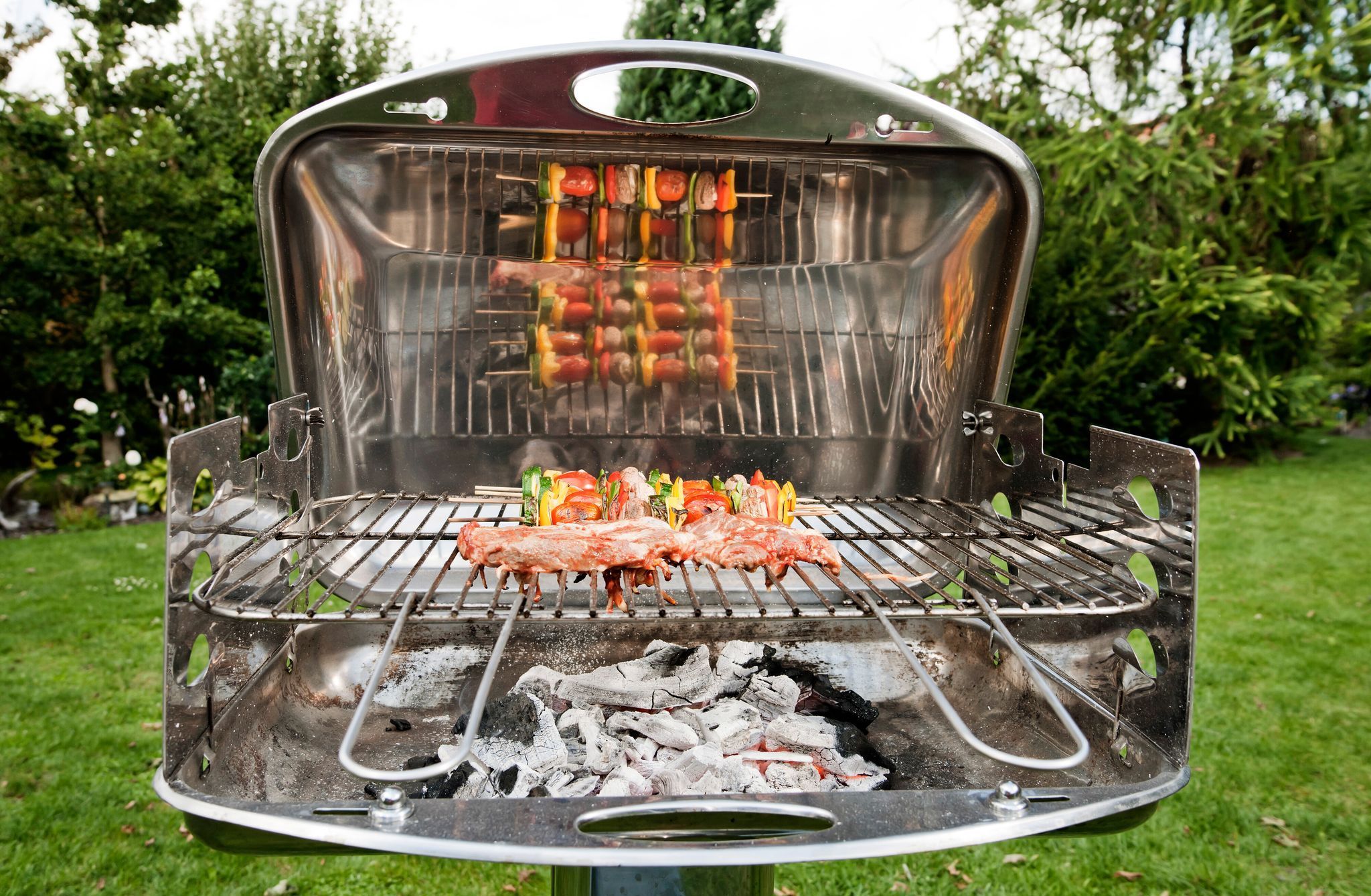 Gemüsespieße und Fleisch liegen auf einem Grill