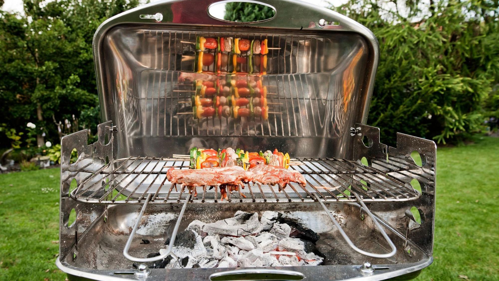 Gemüsespieße und Fleisch liegen auf einem Grill