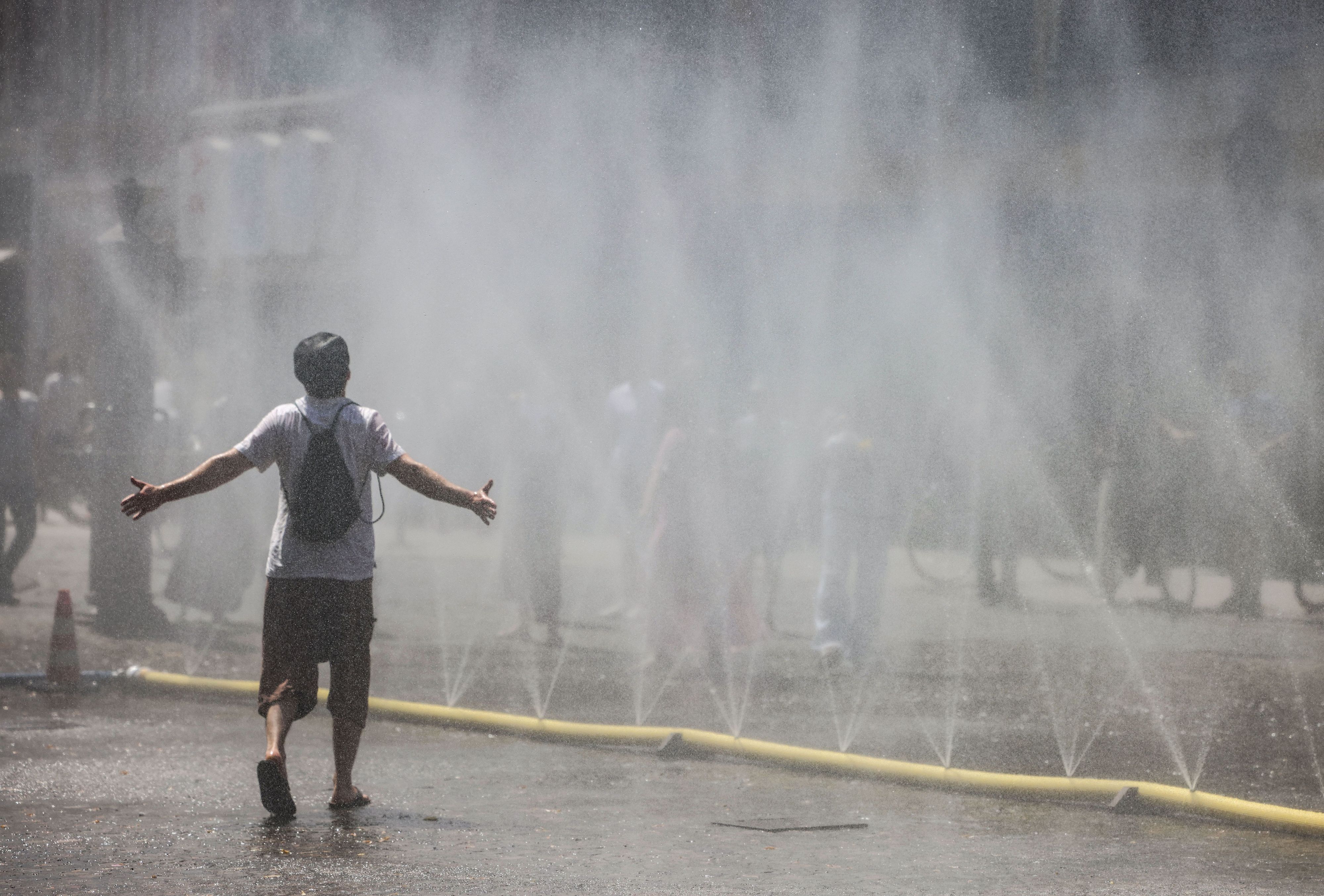 Ein Mann geht durch den Wassernebel in der Kölner Südstadt.
