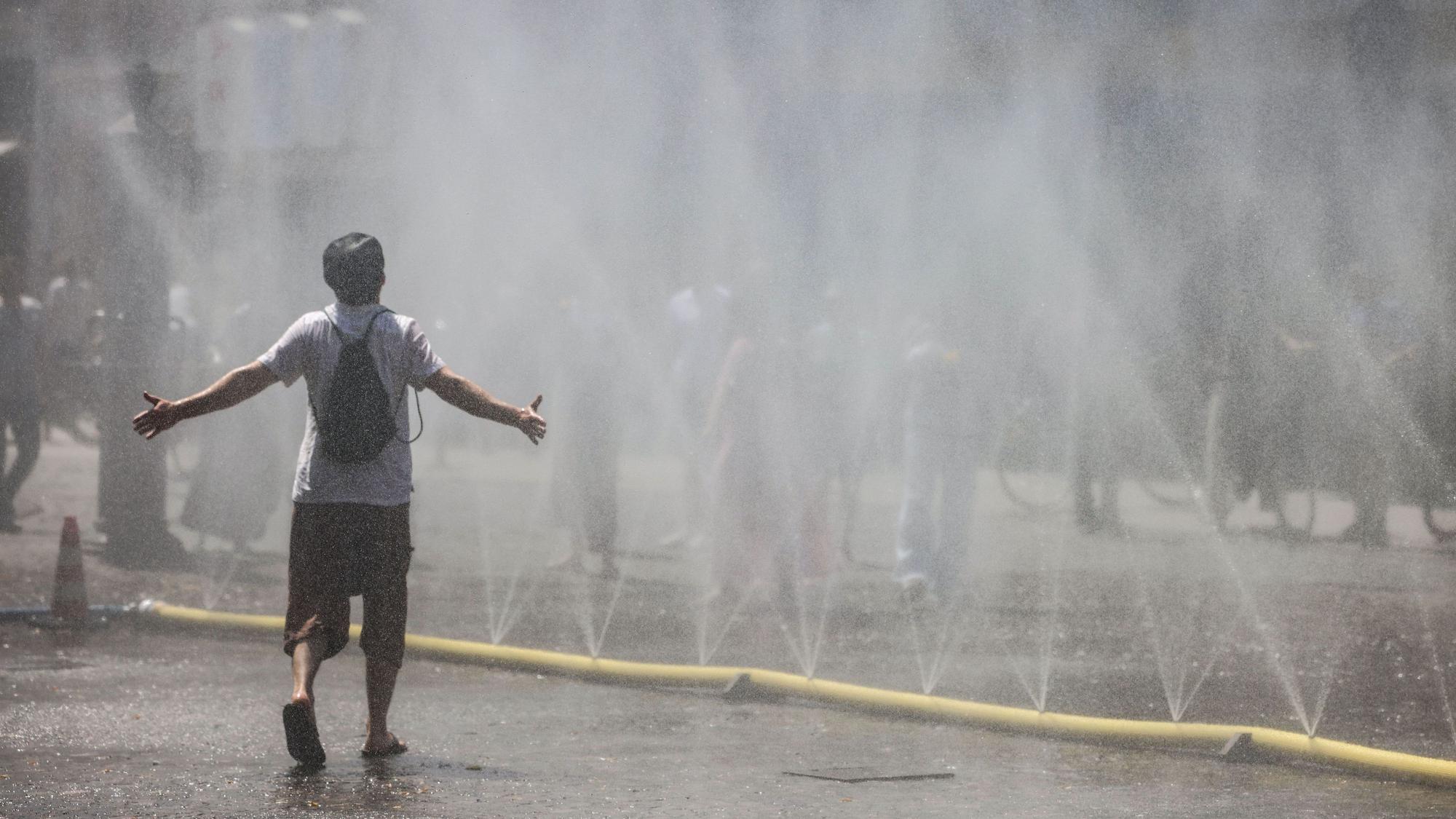 Ein Mann geht durch den Wassernebel in der Kölner Südstadt.