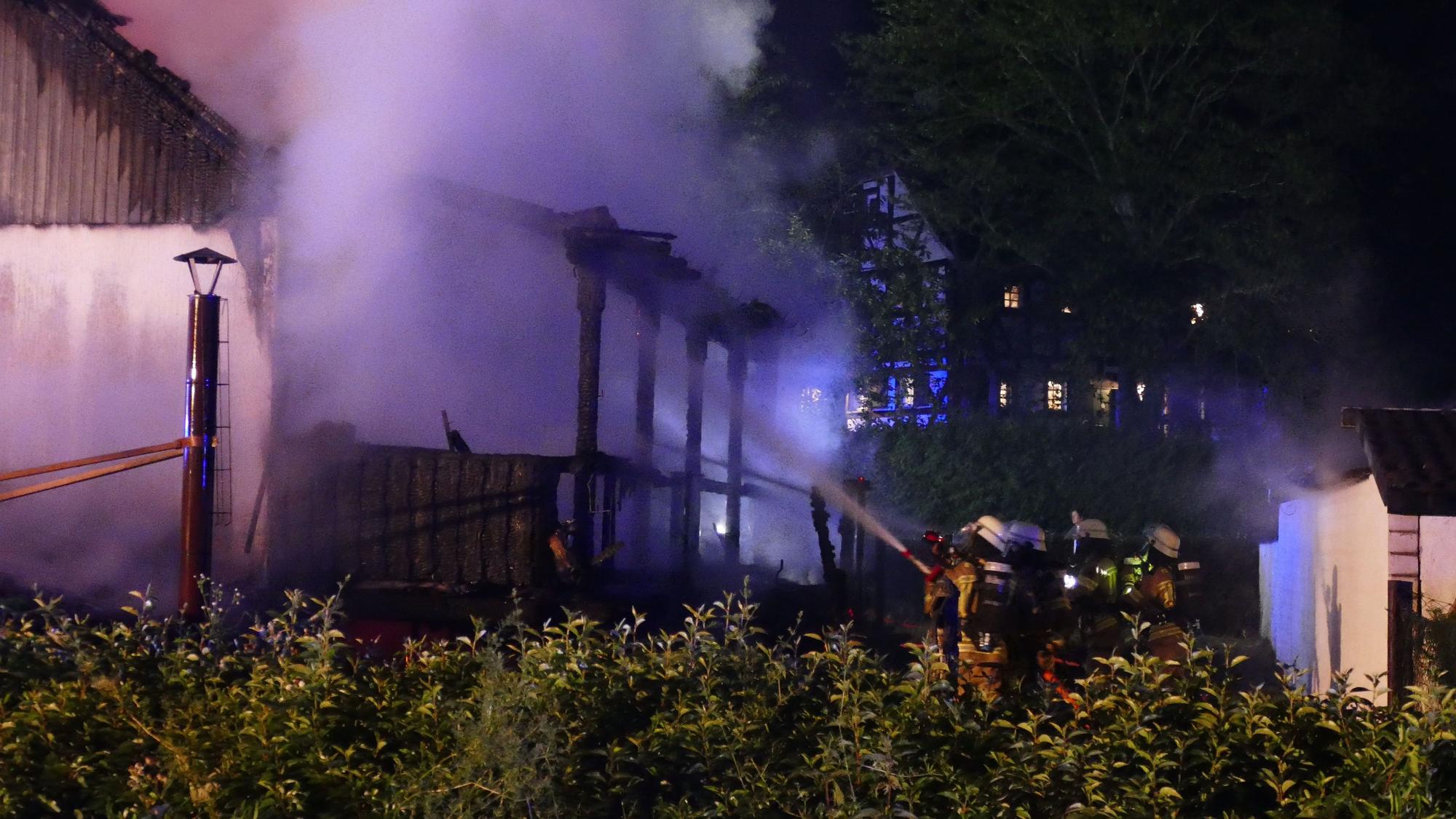 Feuerwehrleute löschen die Terrasse vom Garten aus.