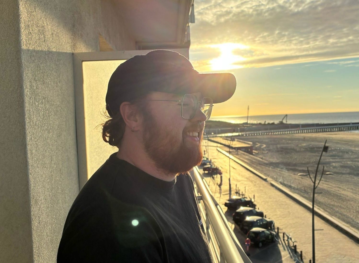 Ein junger Mann steht draußen, im Hintergrund geht die Sonne unter