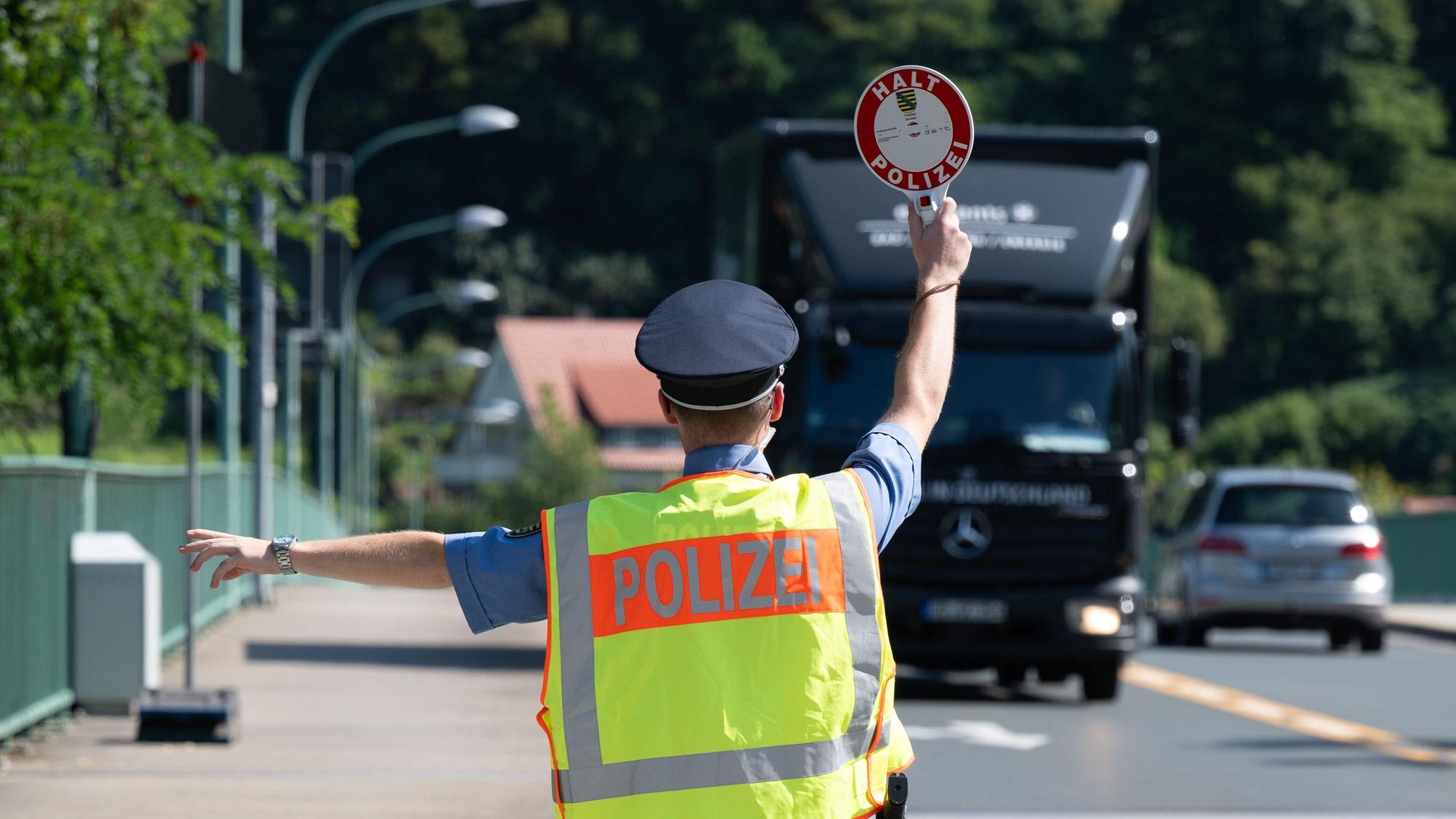 Ein Polizist holt einen Lkw aus dem Verkehr (Symbolfoto).