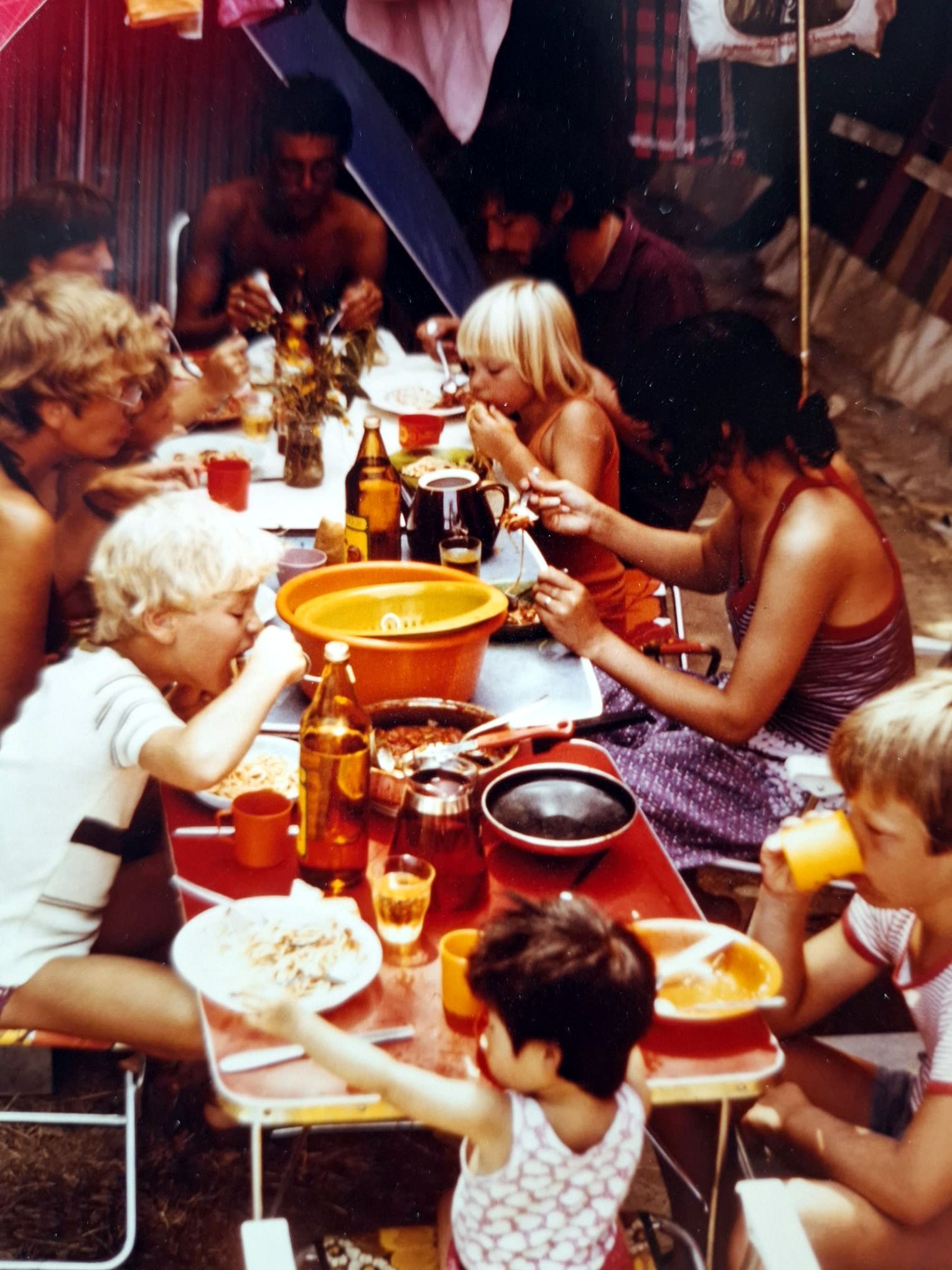 Zu sehen sind Leute, die am Tisch sitzen und essen. Vor allem Kinder.