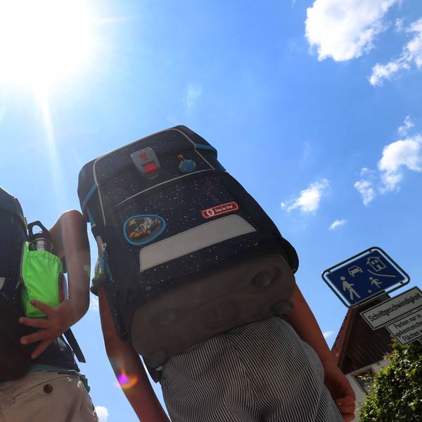 Zwei Kinder laufen mit ihren Büchertaschen im Sonnenschein. Sehr hohe Temperaturen führen an Schulen zu Hitzefrei – aber das ist keine Dauerlösung. (Symbolbild)