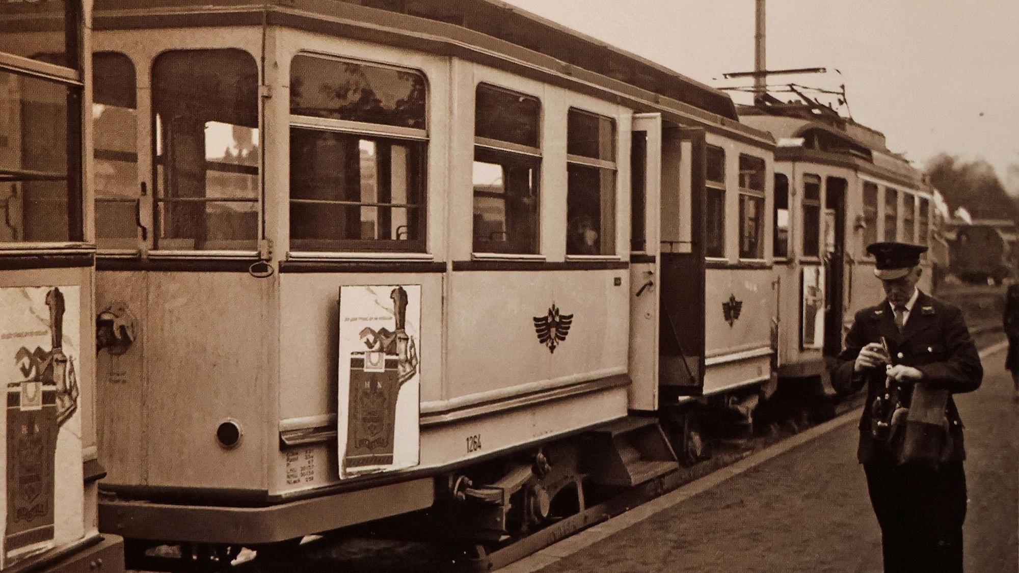 Das alte Foto zeigt einen Mann vor einer Bahn.