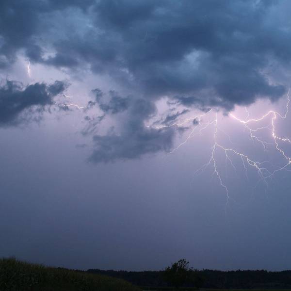 Ein Blitz zuckt bei einem Sommergewitter am abendlichen Himmel.