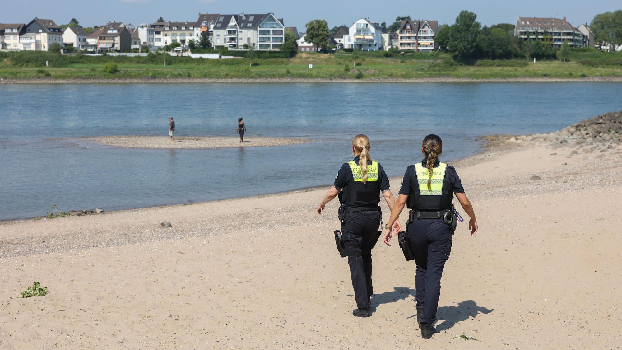 Mitarbeiterinnen des Ordnungsamts kontrollieren das Badeverbot im Rhein.