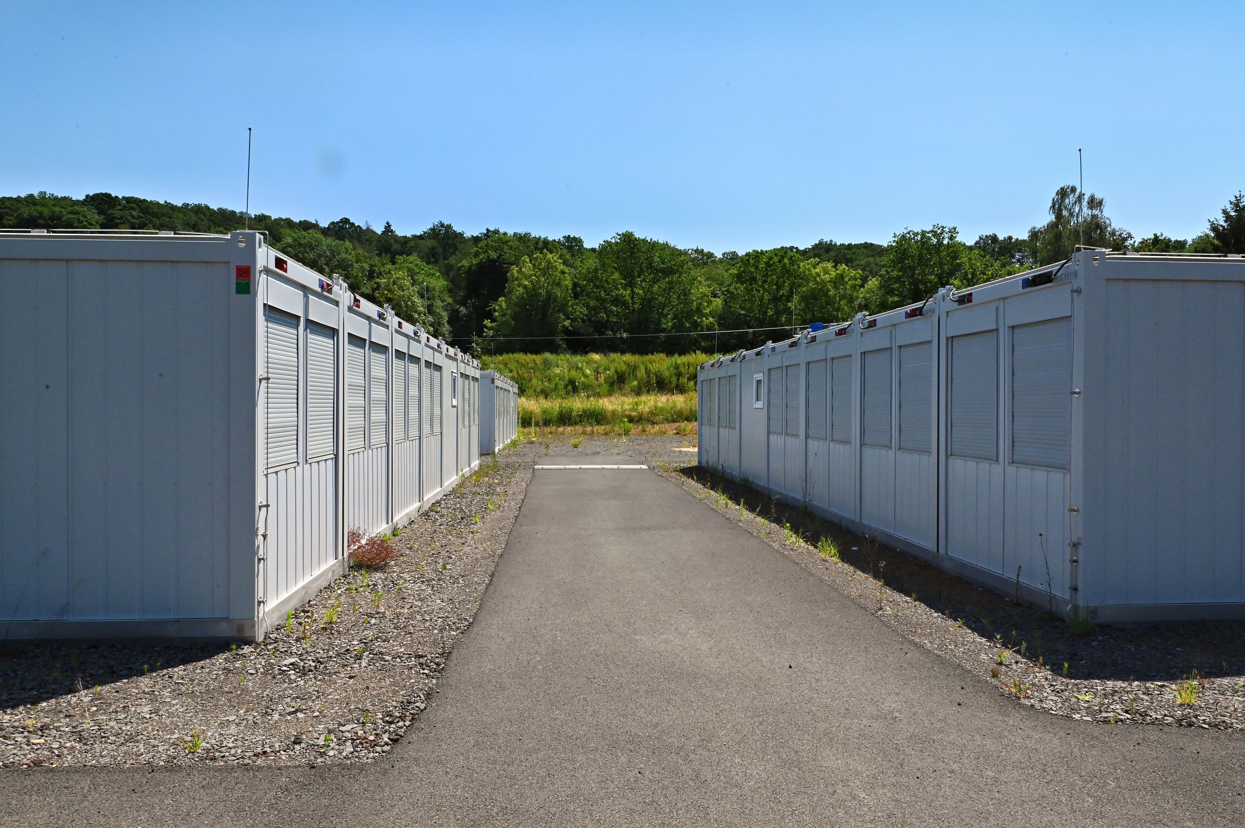 Rechts und links eines asphaltierten Weges stehen Container für Geflüchtete und Obdachlose.