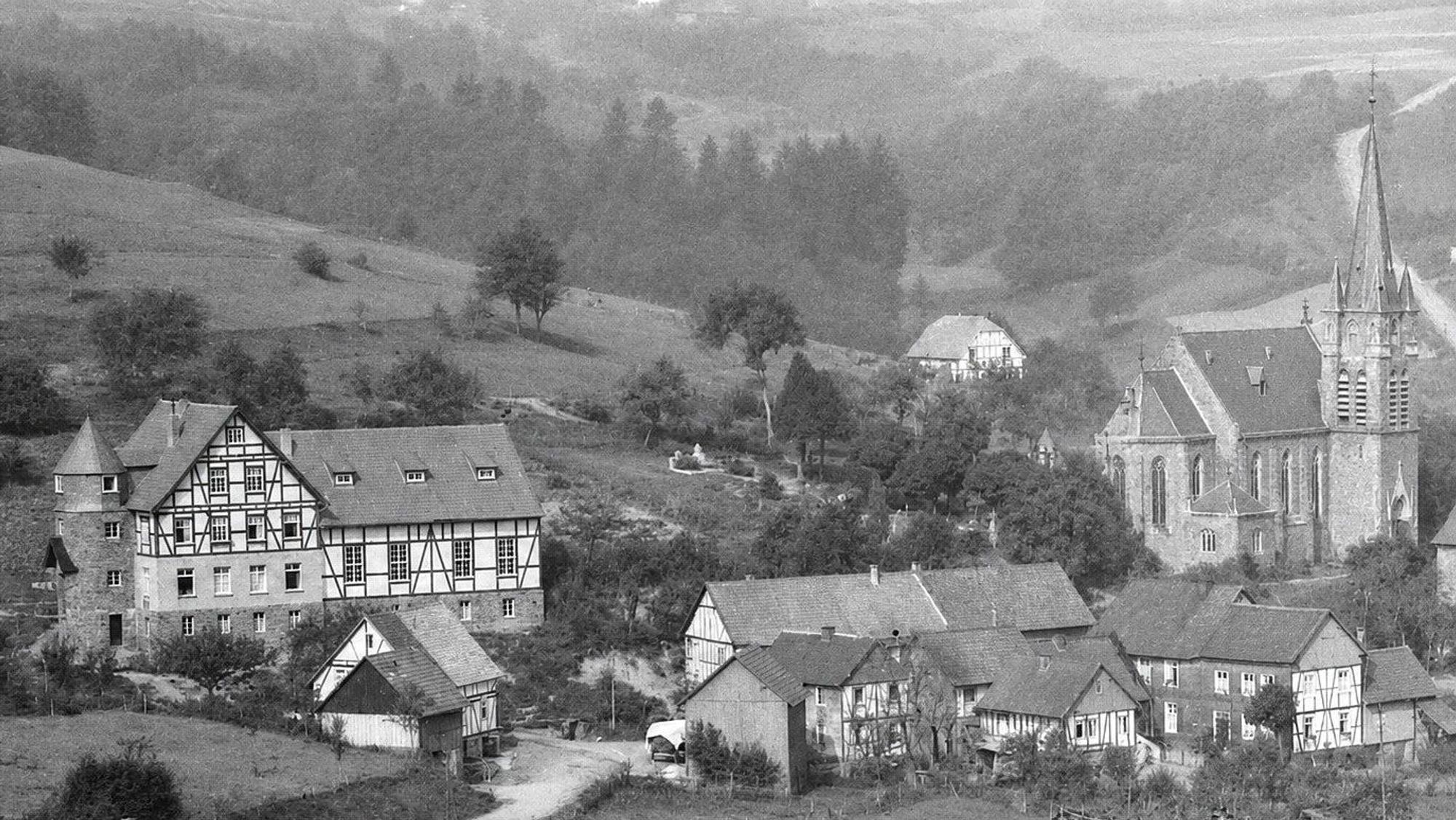 Dieses historische Foto aus Morsbach zeigt das Gesellenhaus in Holpe (links) in den 1930er Jahren. Vor 100 Jahren wurde der Grundstein gelegt, was am 28. Juni 2026 in der Kirche St. Mariä Heimsuchung (rechts) mit einem Gottesdienst gefeiert wird.
