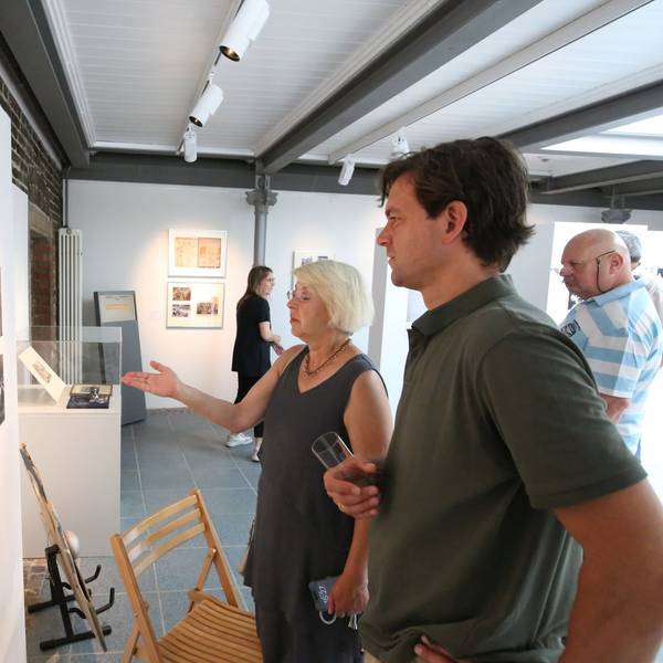Ein Mann und eine Frau betrachten historische Schwarz-Weiß-Fotos in einer Ausstellung.