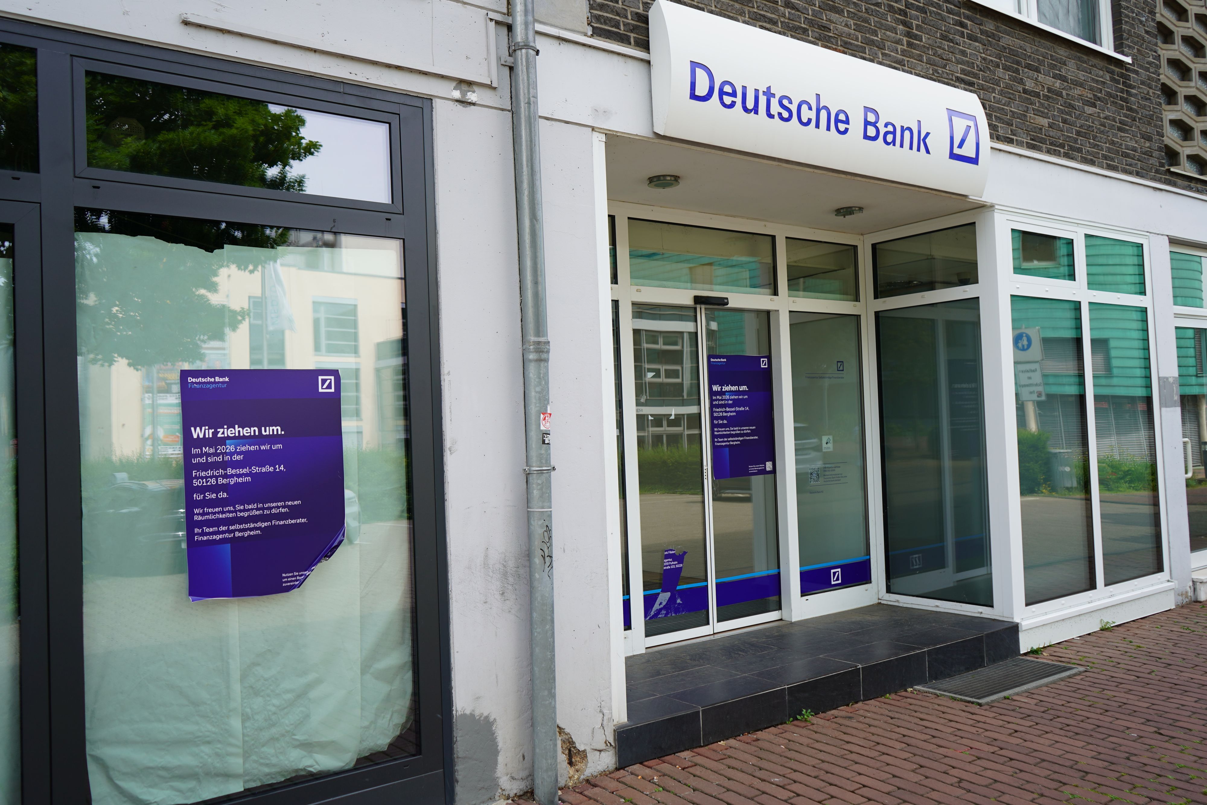 Das Bild zeigt eine Filiale der Deutschen Bank. Es hängt ein Zettel mit der Aufschrift "Wir ziehen um".
