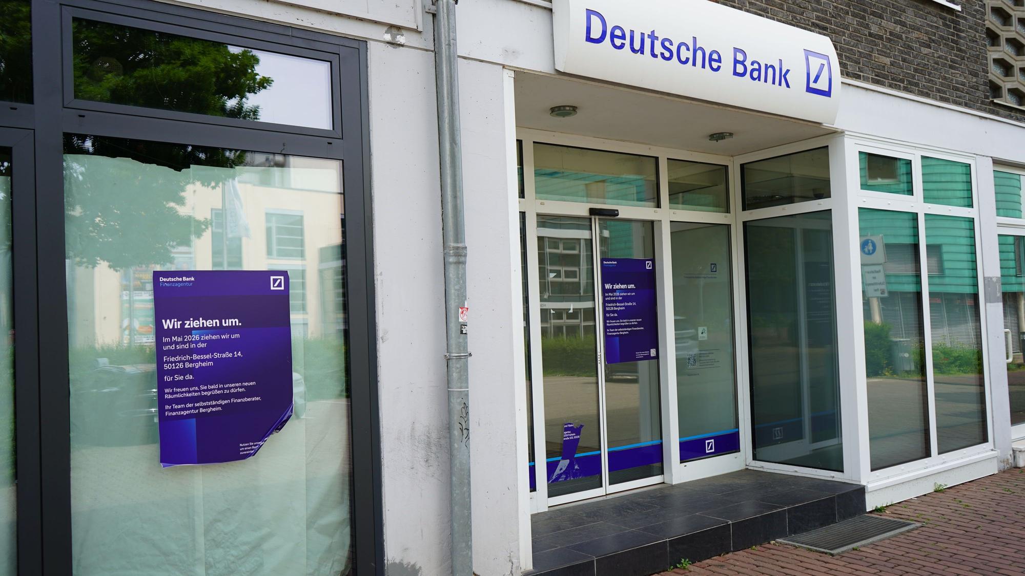 Das Bild zeigt eine Filiale der Deutschen Bank. Es hängt ein Zettel mit der Aufschrift "Wir ziehen um".