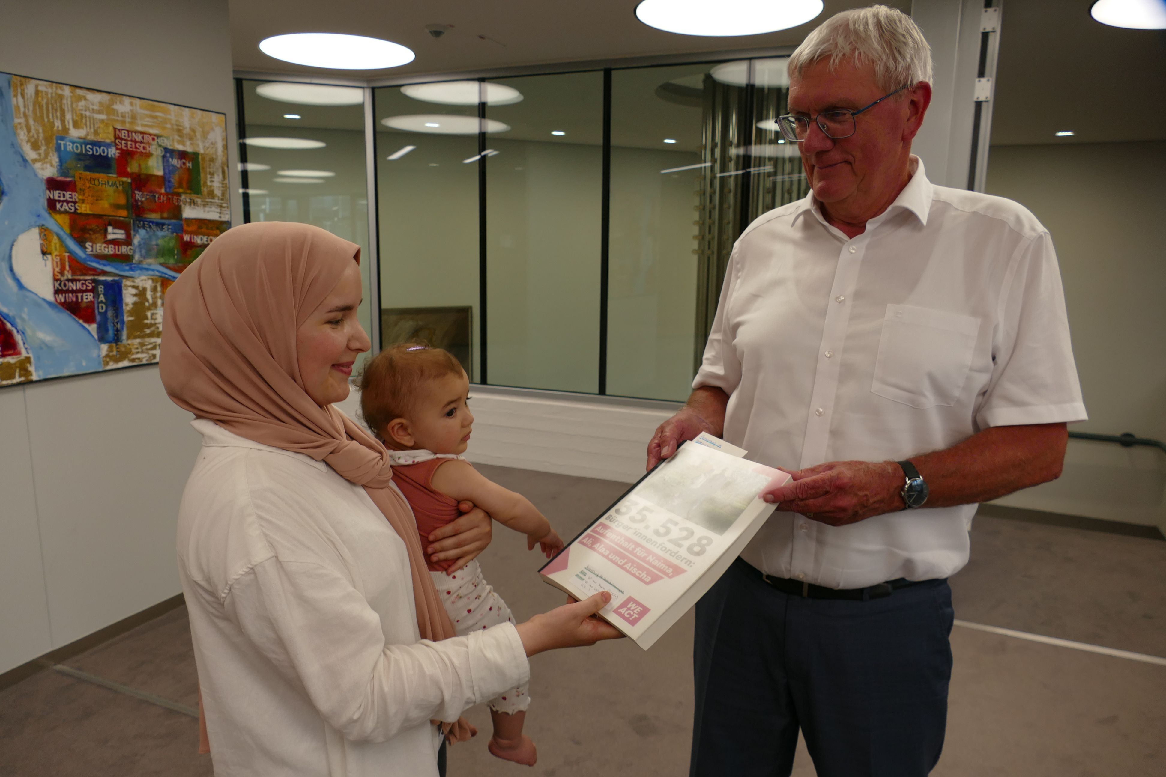 Naima Farhane, mit der kleinen Aischa auf dem Arm, übergibt Landrat Sebastian Schuster die Petition mit 35.528 Unterschriften.